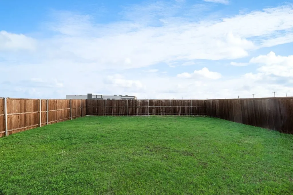 Spacious grassy yard enclosed by a tall wood privacy fence