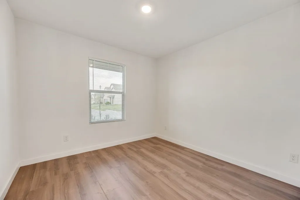Room featuring wood-finish flooring, white baseboards, a white ceiling, and a recessed ceiling light