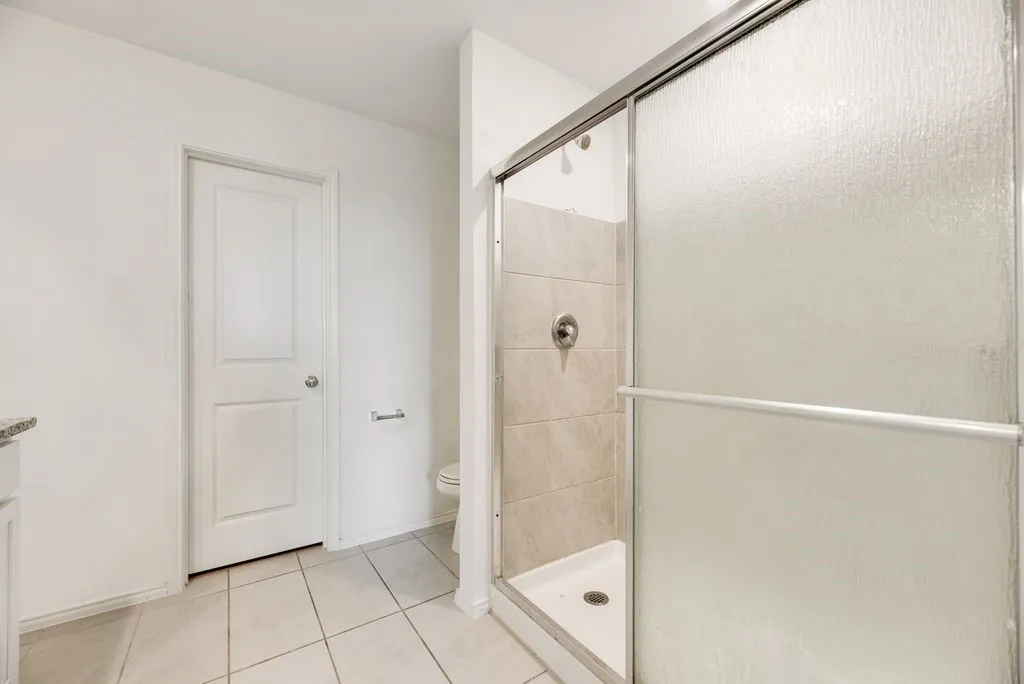 Shower enclosure with textured glass doors, tiled walls, and a chrome shower fixture