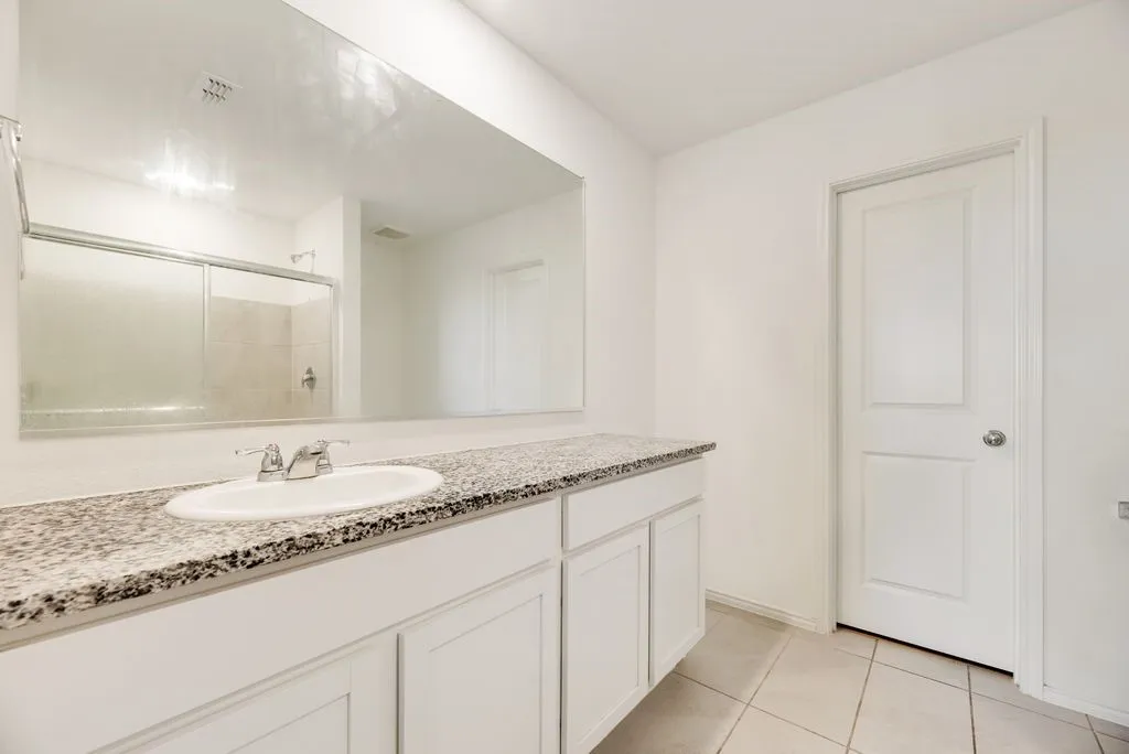 Bathroom vanity featuring white cabinetry, a speckled countertop, and an undermount sink