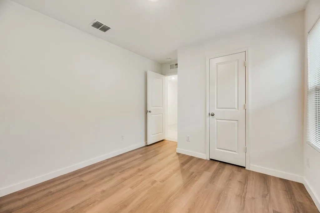 Bedroom featuring wood-finish flooring, white baseboards, and neutral wall paint