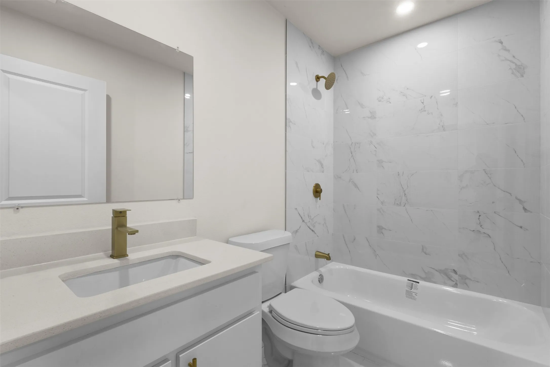 White vanity with integrated sink, gold-finish faucet, and coordinating gold-finish hardware