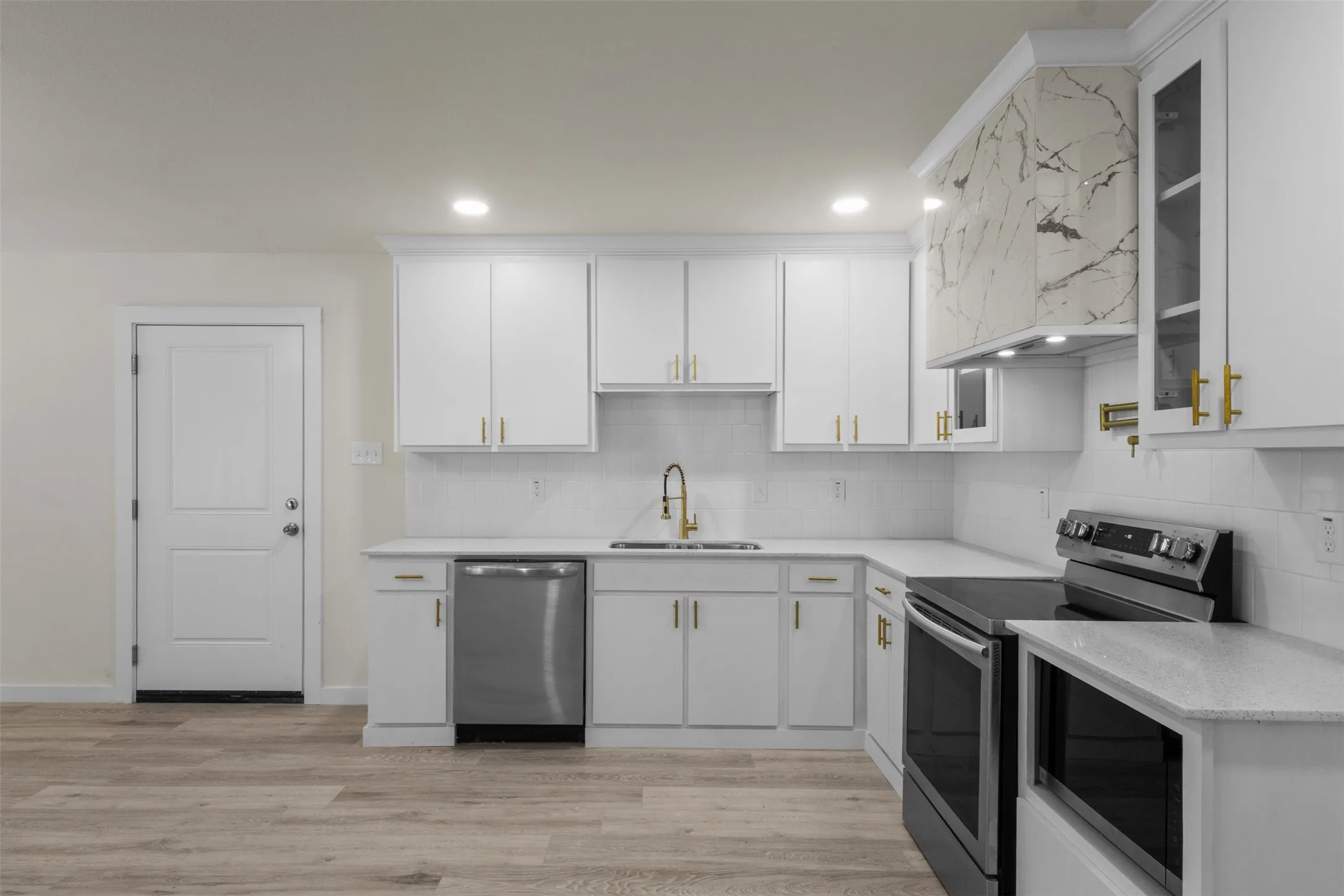 Kitchen featuring white shaker cabinetry, light-toned countertops, tile backsplash, and wood-finish flooring