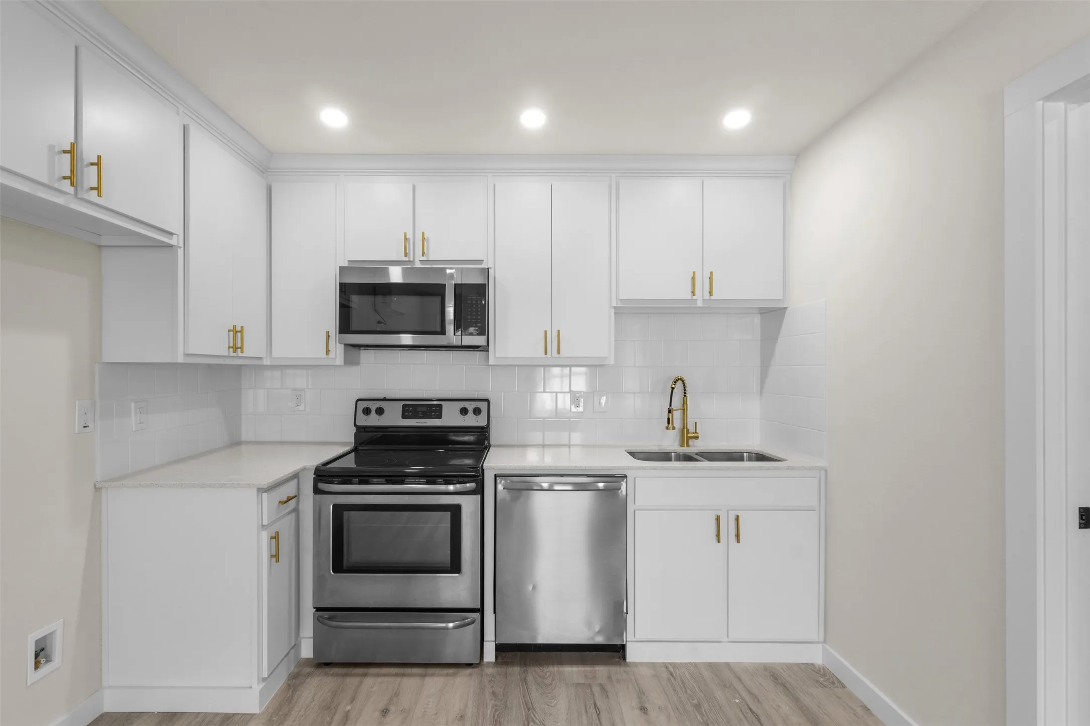 Kitchen featuring white cabinetry, stainless steel appliances, a white tile backsplash, and wood-finish flooring