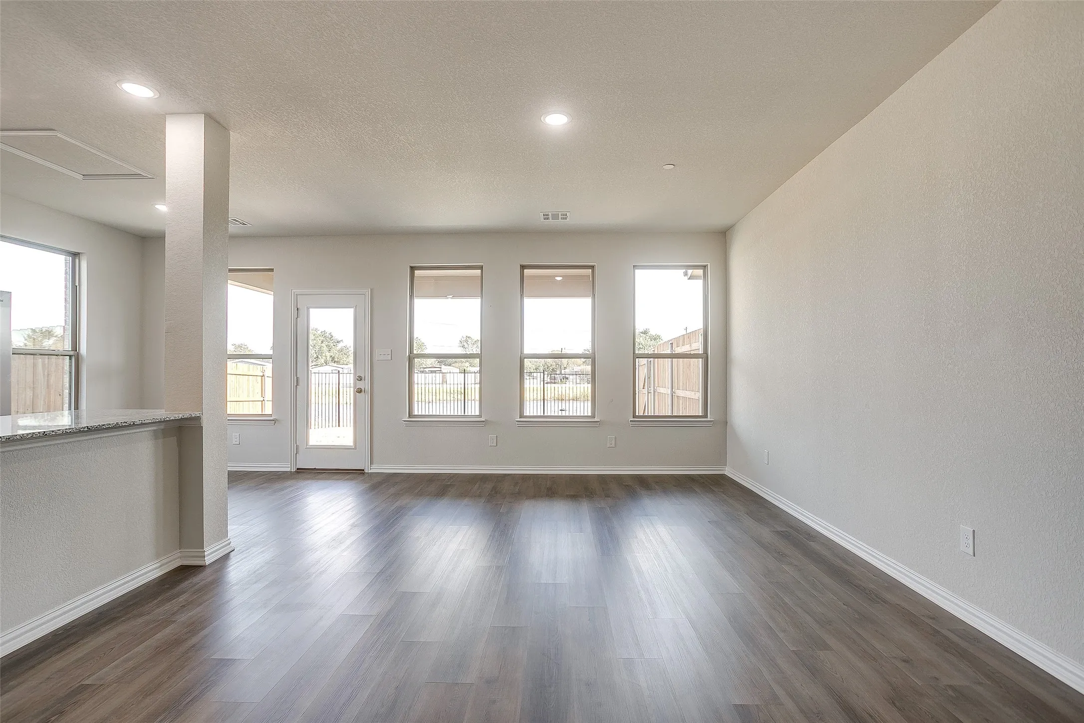Unfurnished room with dark wood-style floors, a textured ceiling, a textured wall, and recessed lighting