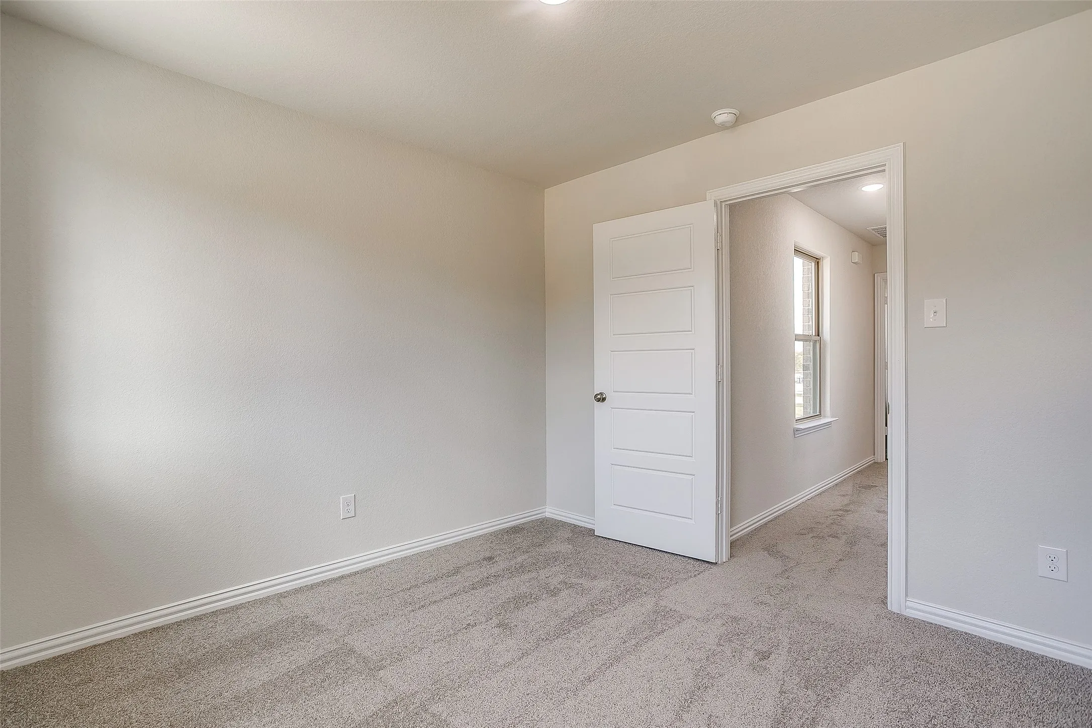 Empty room with light colored carpet and baseboards