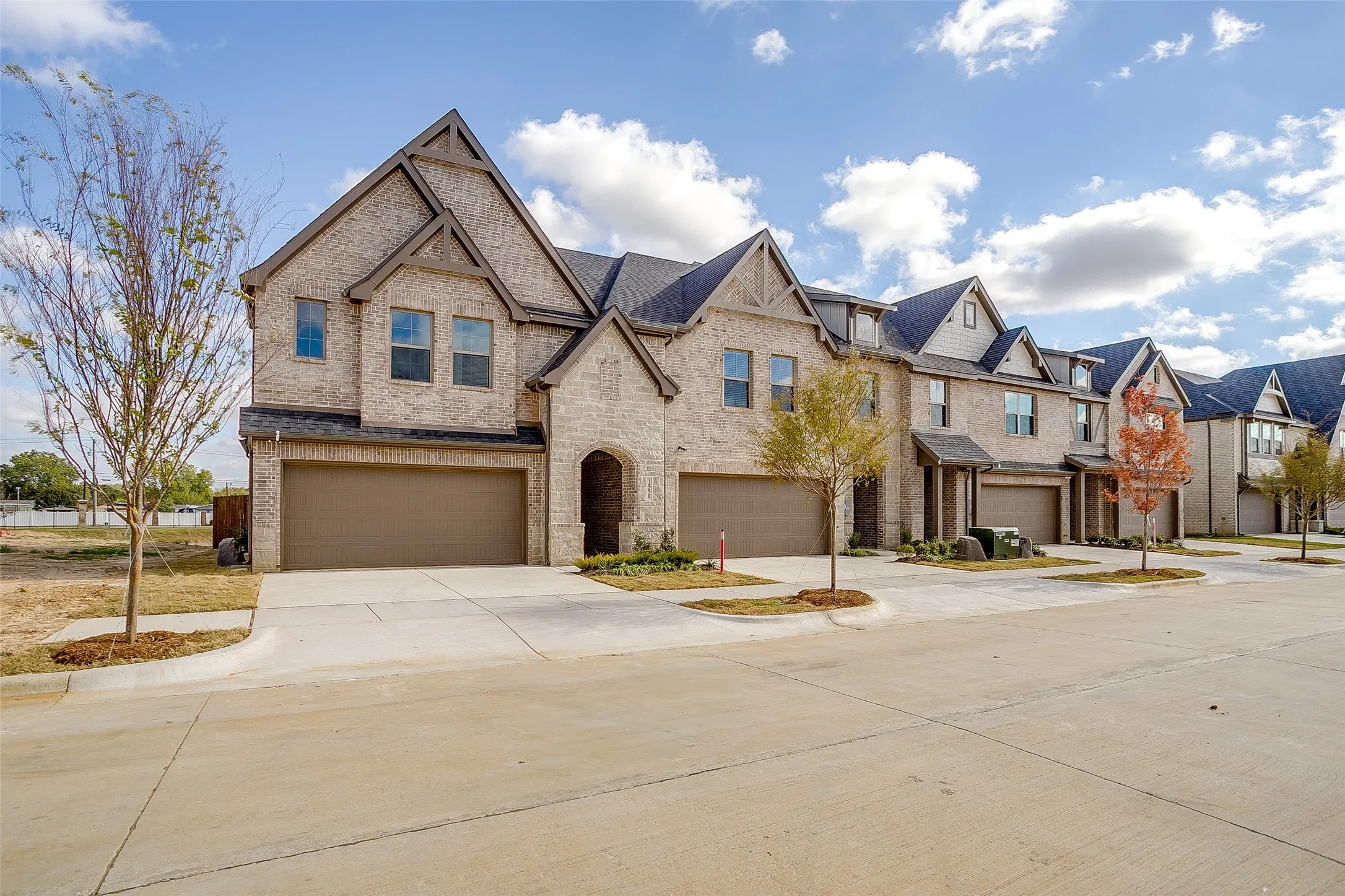 View of front of property with brick siding, driveway, an attached garage, and a residential view