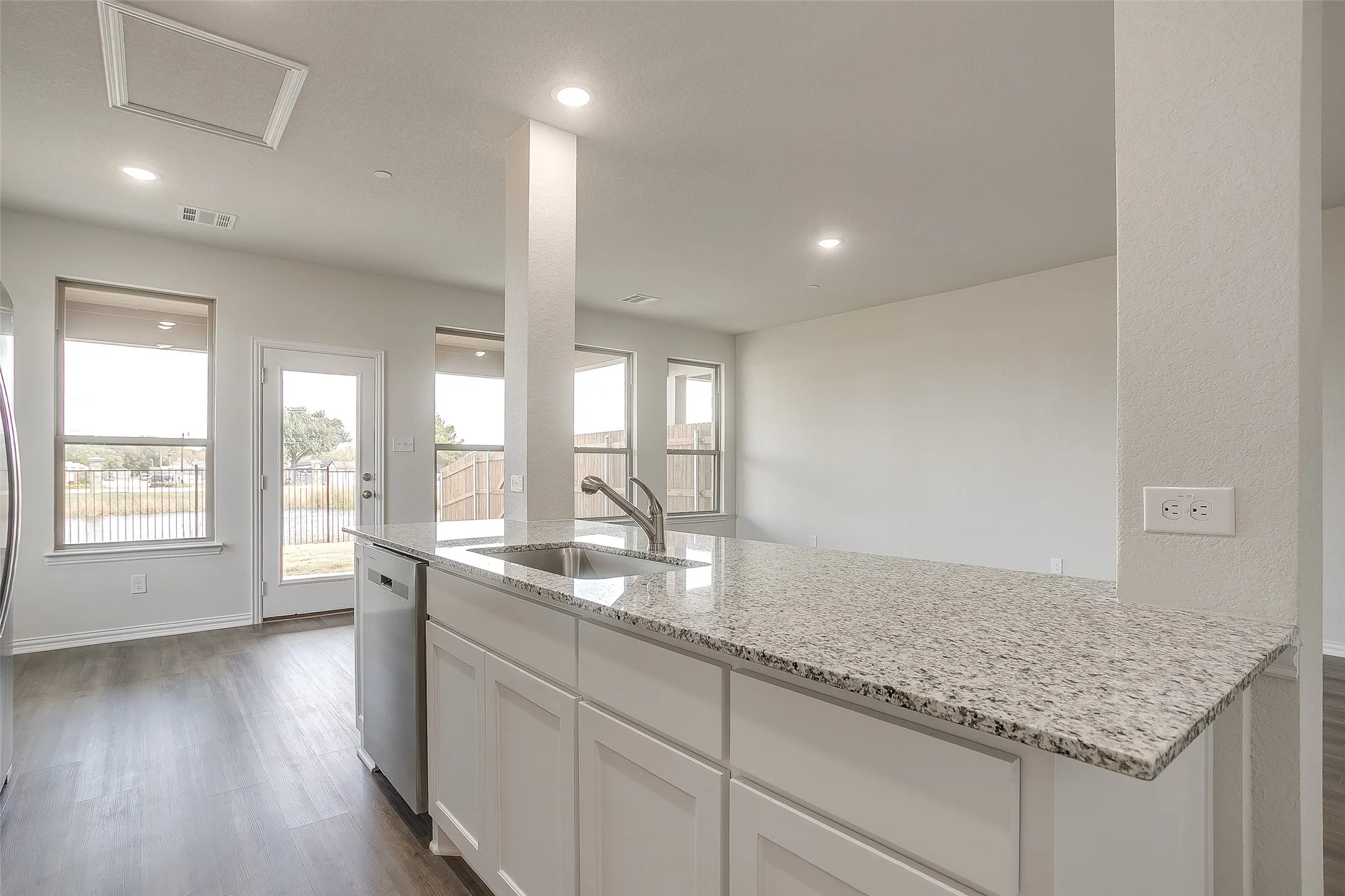 Kitchen with dark wood-style flooring, light stone countertops, white cabinets, dishwasher, and recessed lighting