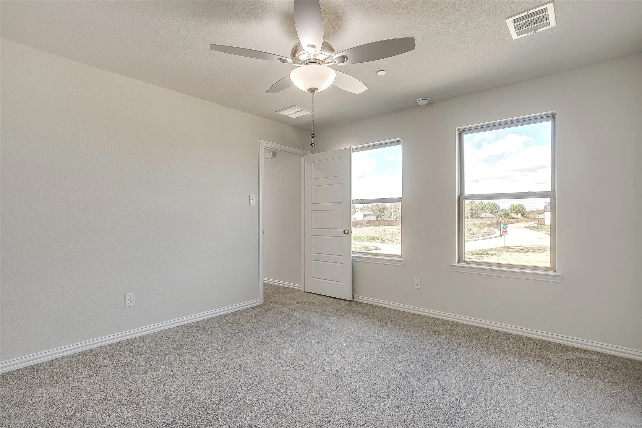 Spare room featuring light carpet and ceiling fan