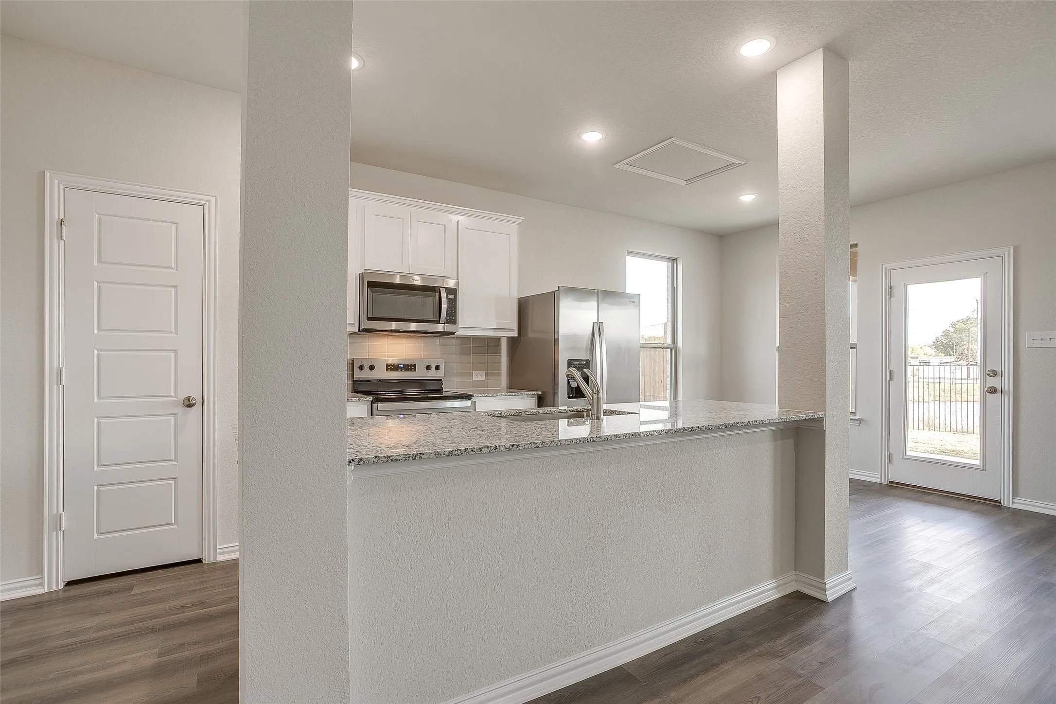 Kitchen featuring light stone counters, decorative backsplash, dark wood finished floors, white cabinetry, and recessed lighting