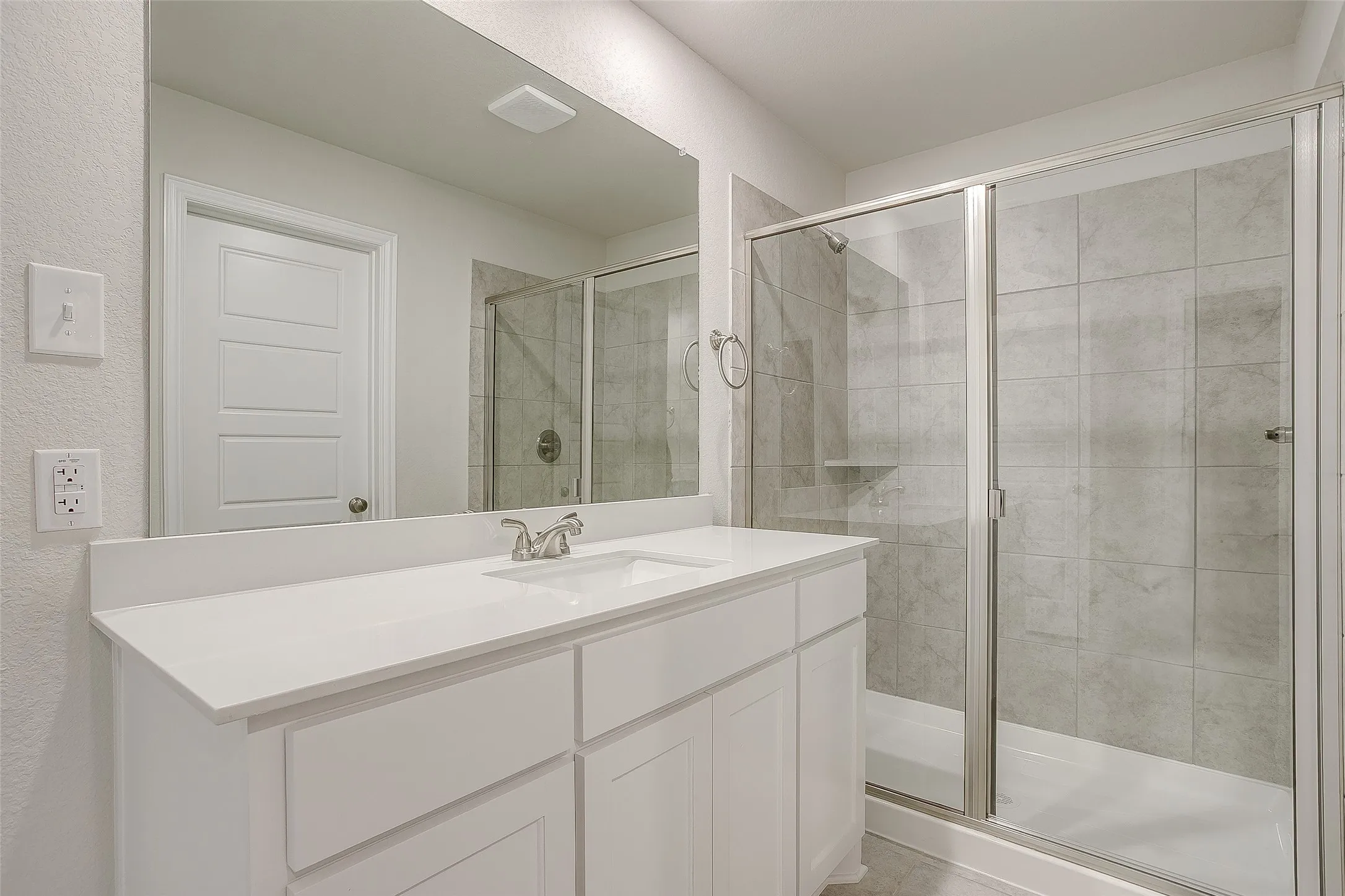 Full bathroom with vanity, a shower stall, and a textured wall