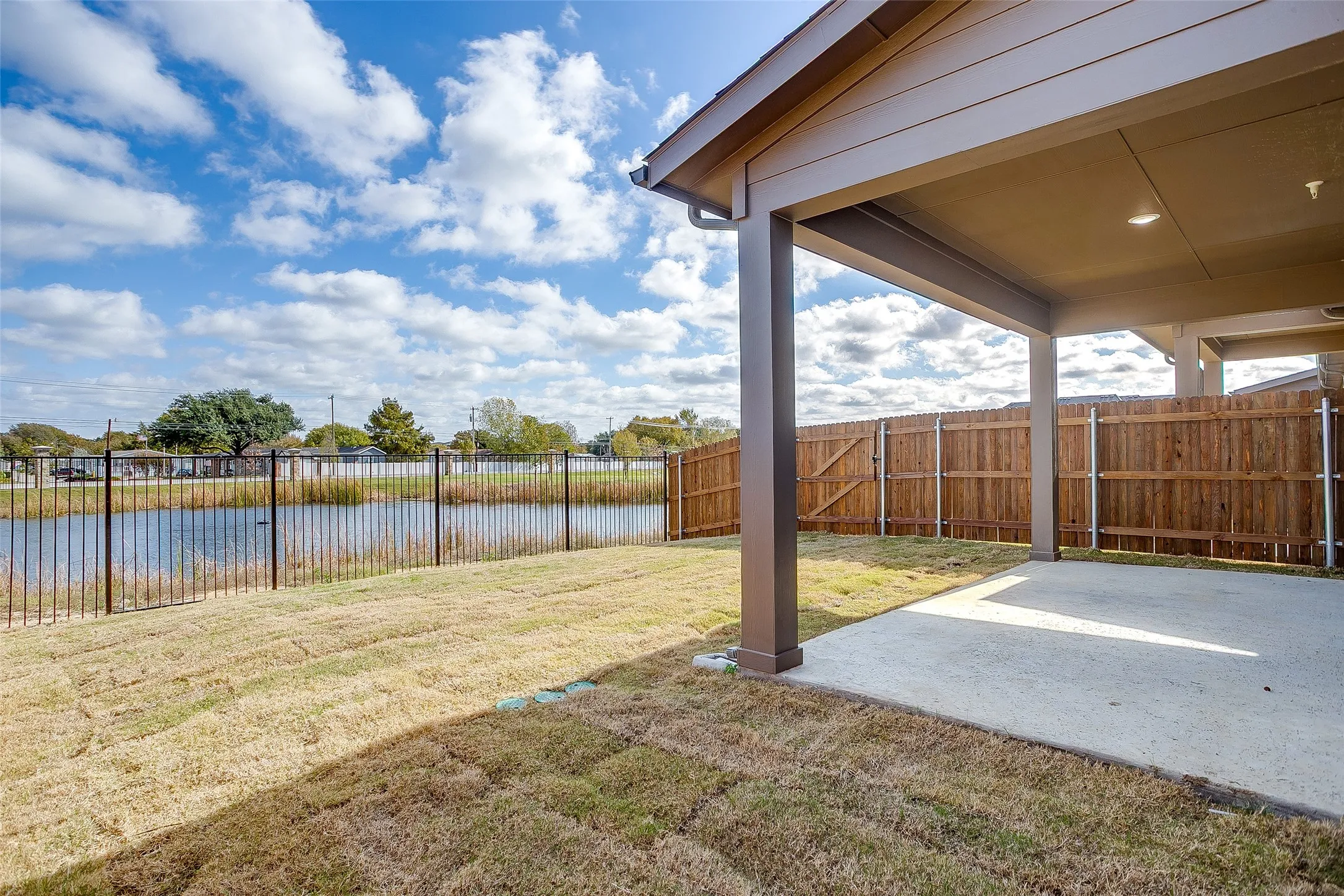 Fenced backyard with a water view and a patio