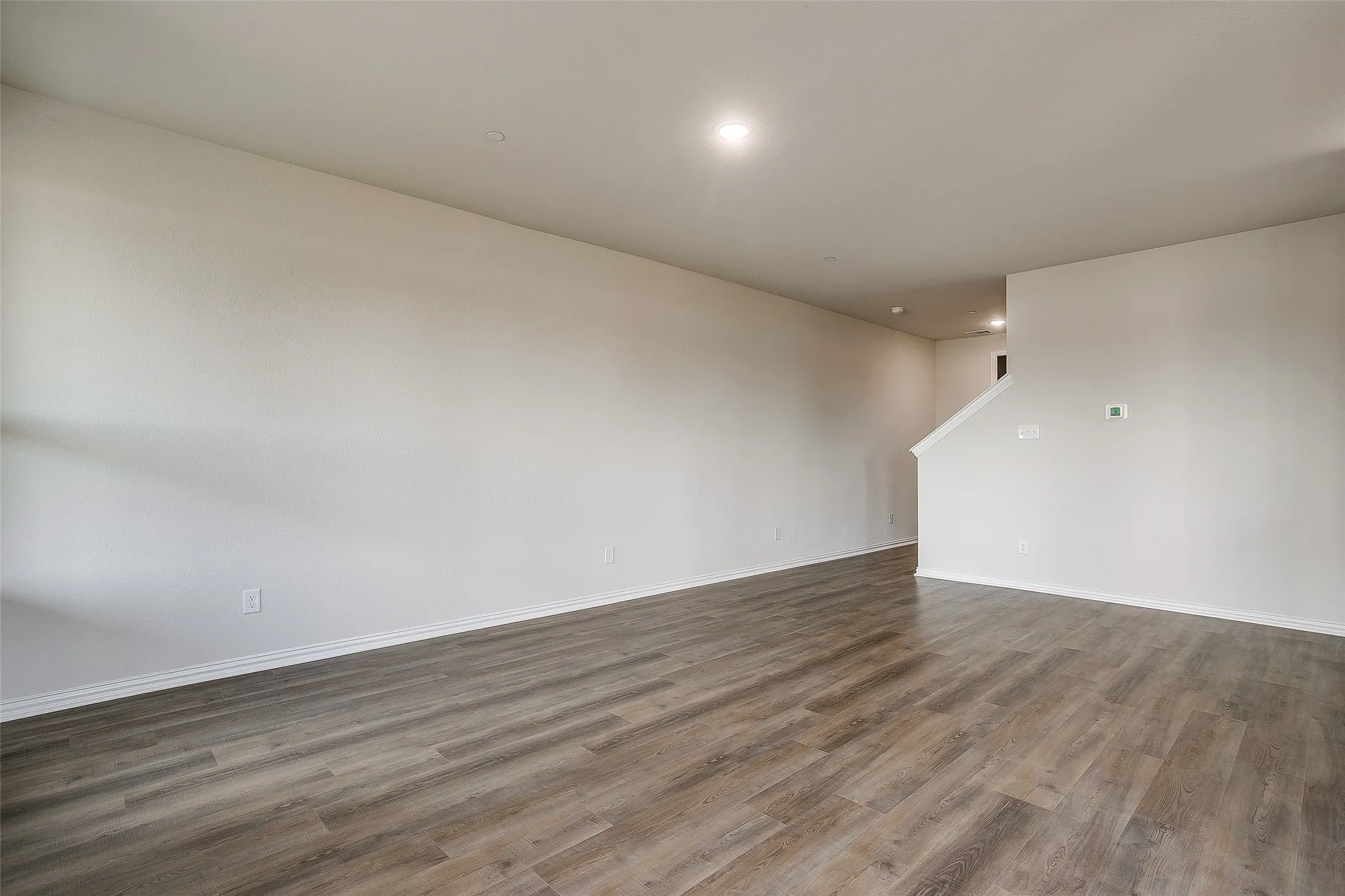 Unfurnished living room with wood finished floors and recessed lighting