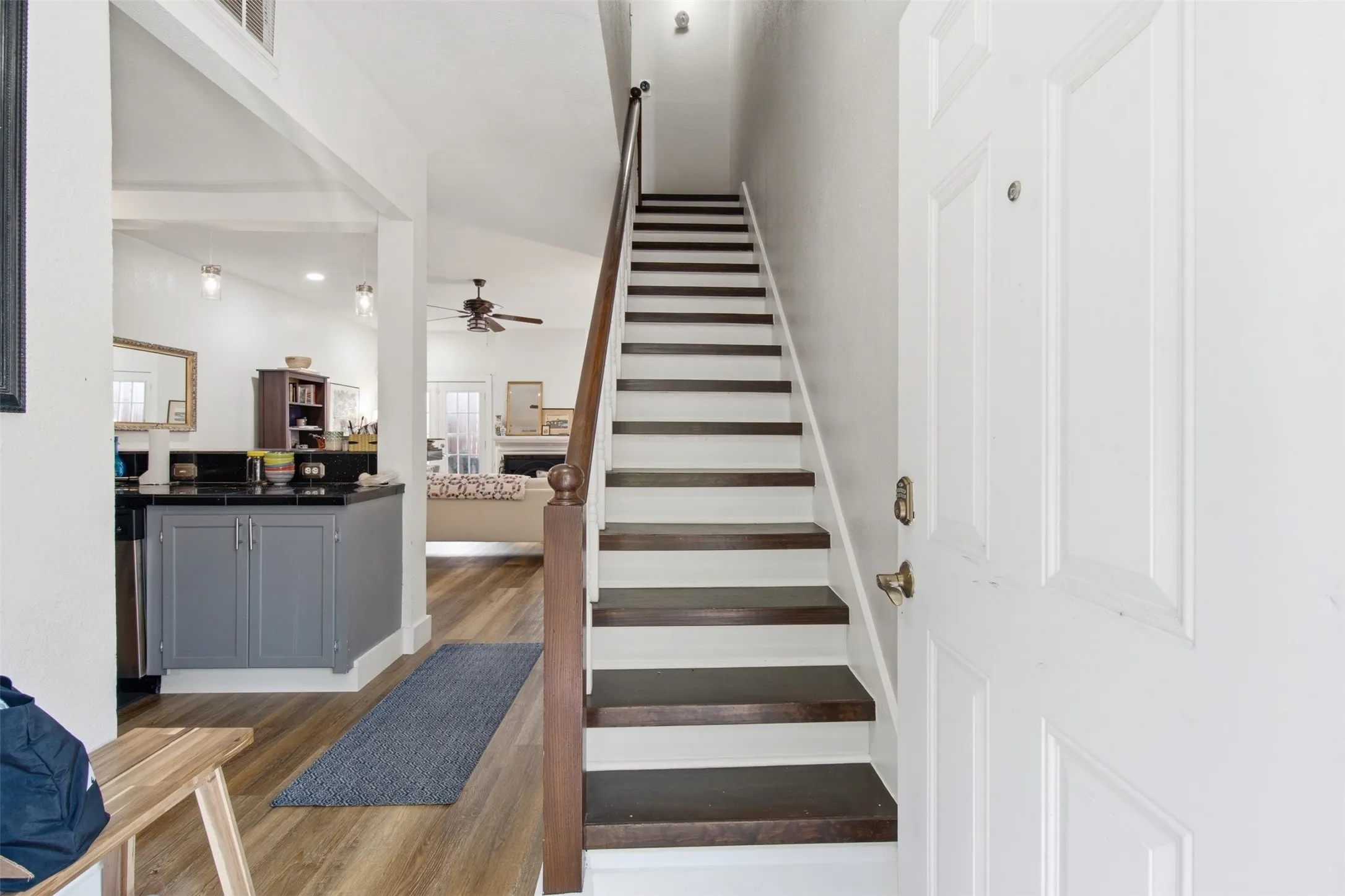 Bright entryway with wide staircase featuring alternating gray and white risers, wood-finish treads, and white railings