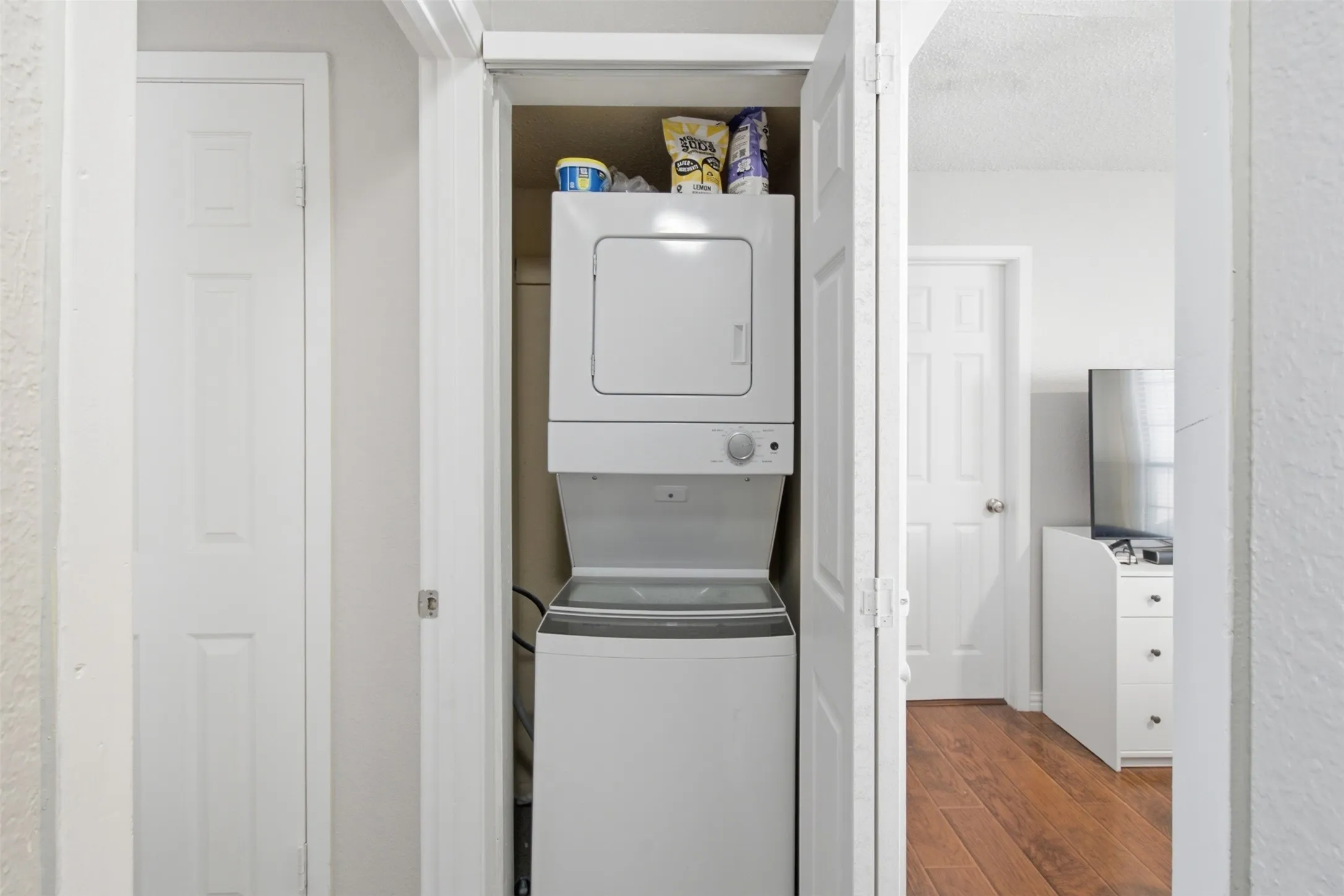 Built-in laundry closet with a stacked white washer and dryer
