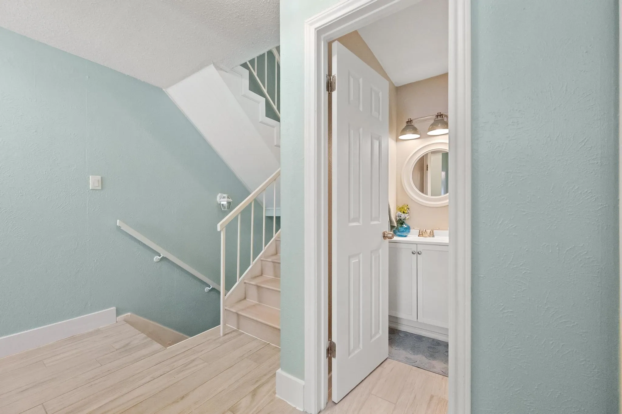 Staircase with a white railing and banister, featuring light-toned flooring on the lower level