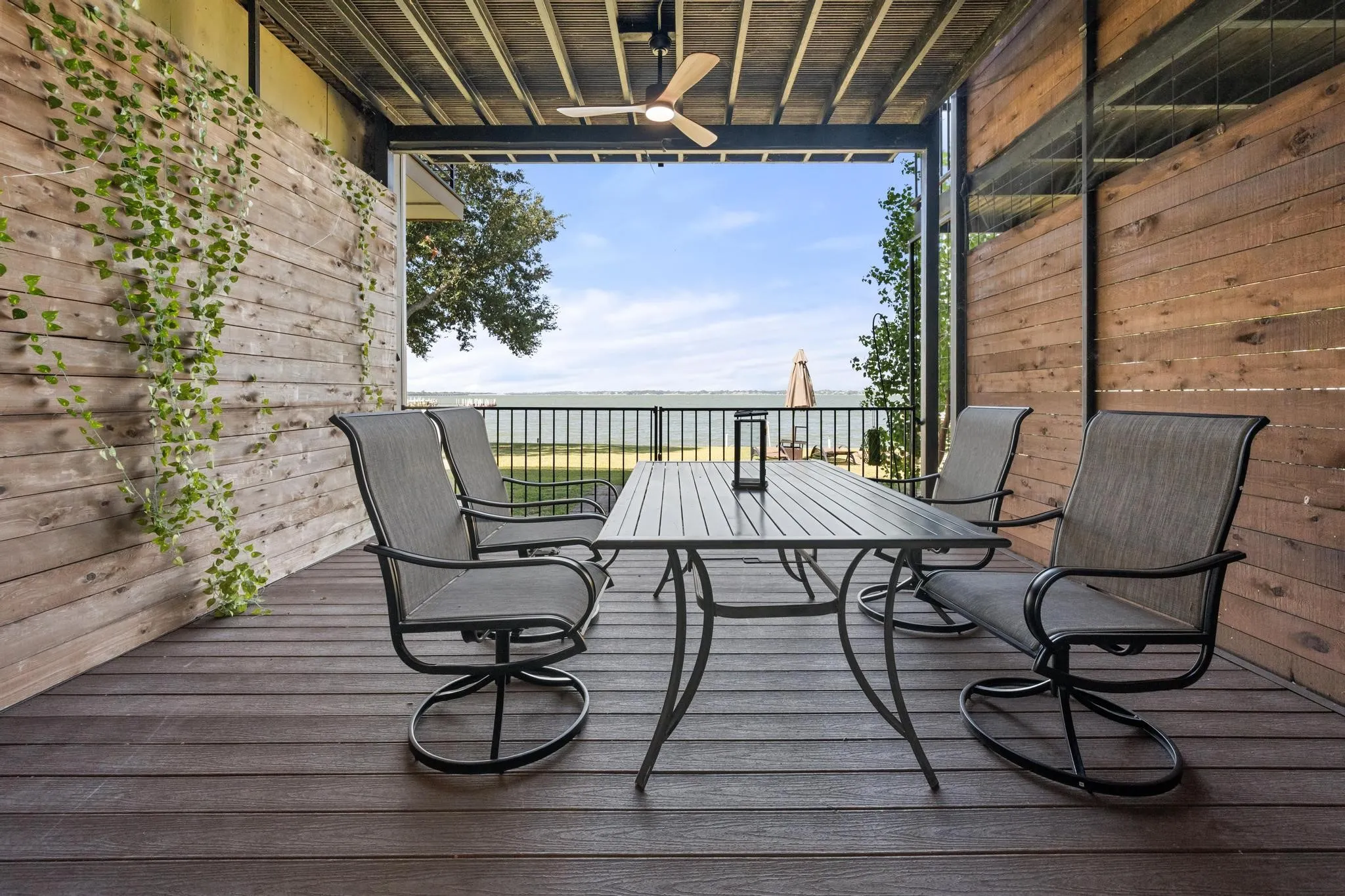 Covered outdoor patio with a ceiling fan, plank wood accent walls, and wood-finish decking