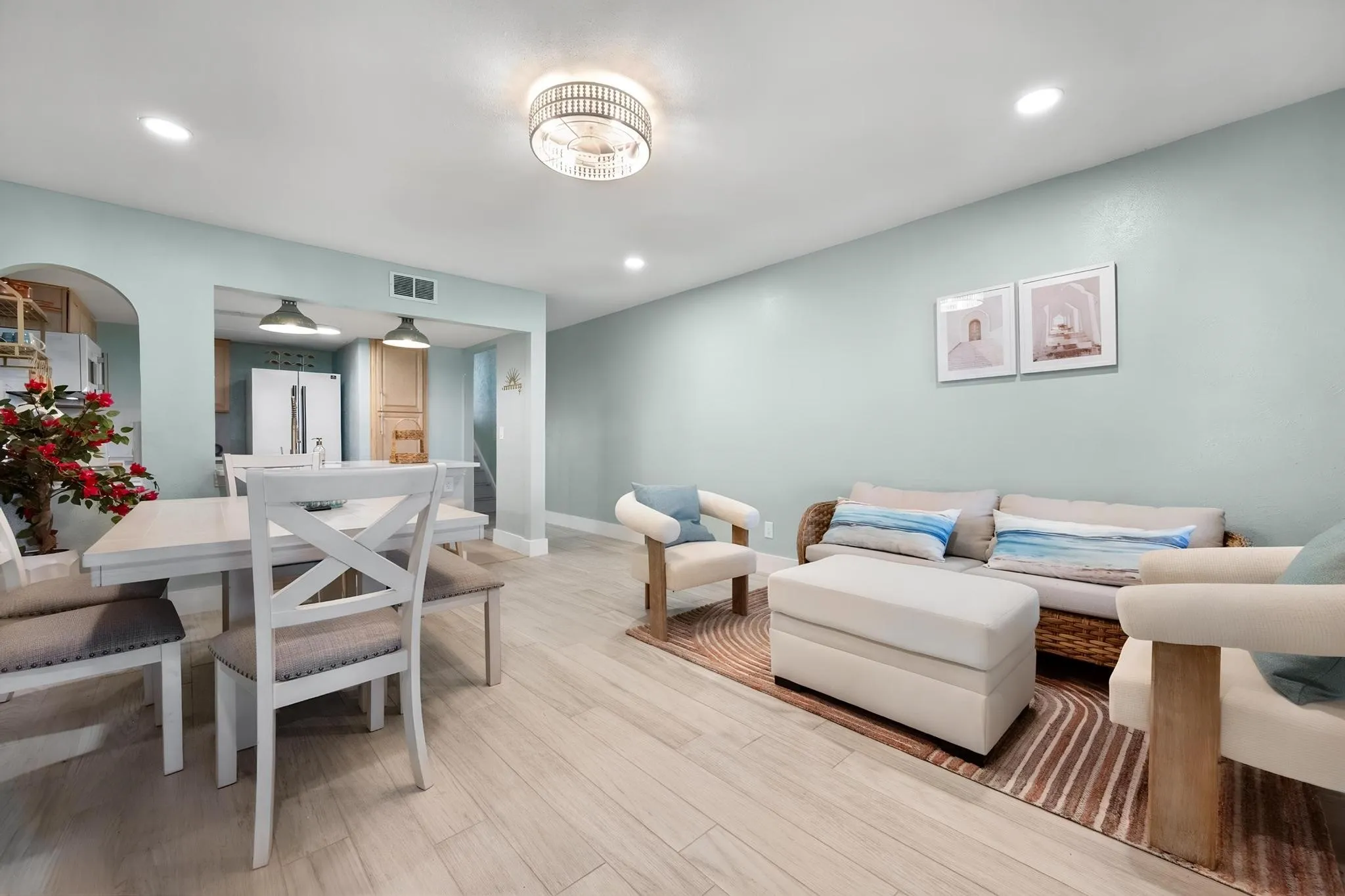Recessed ceiling lighting, wood-finish flooring, two-tone wall paint, built-in kitchen cabinetry, and an arched entryway