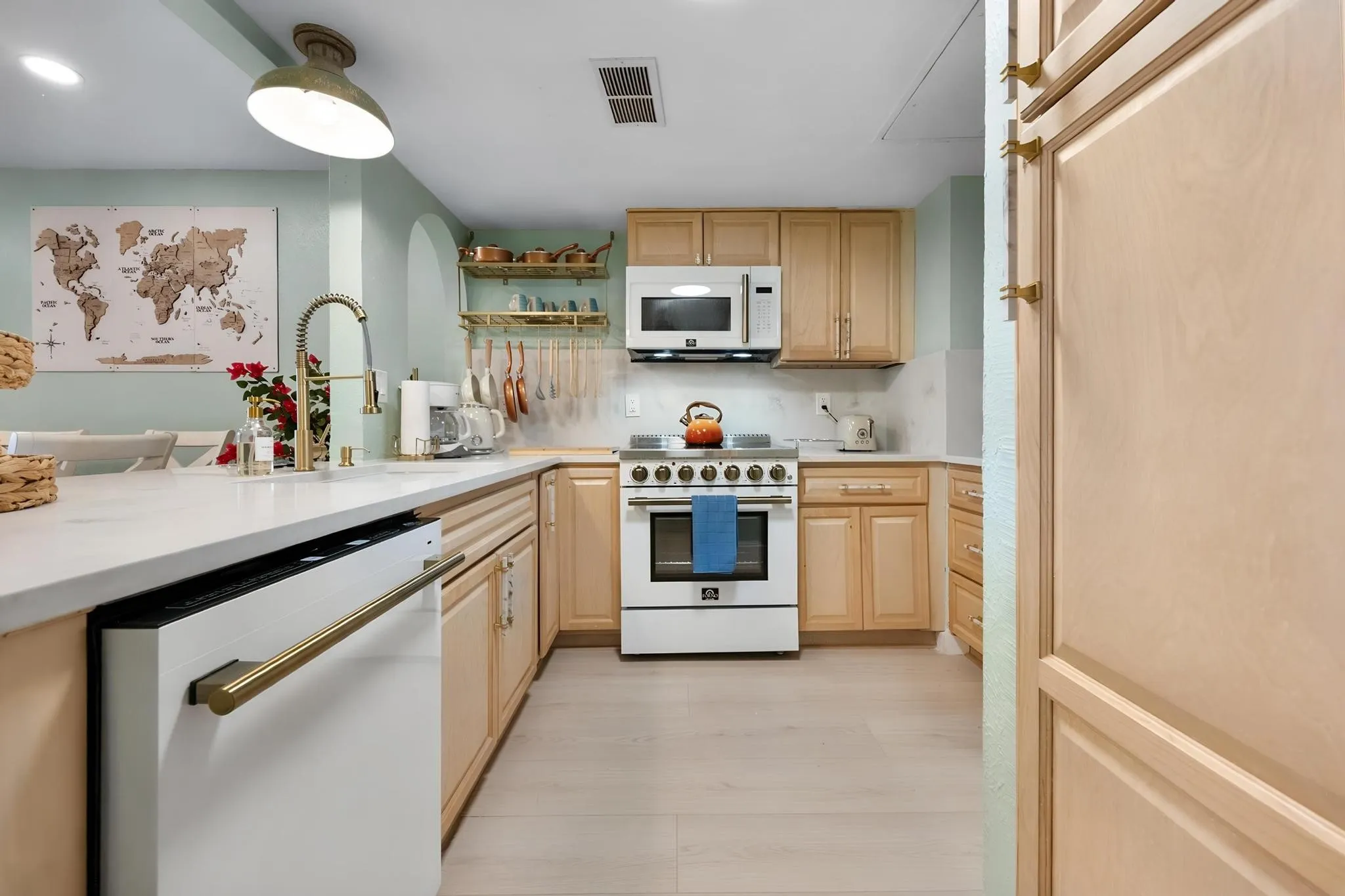 Kitchen featuring light wood cabinetry, white countertops, stainless steel appliances, and wood-finish flooring