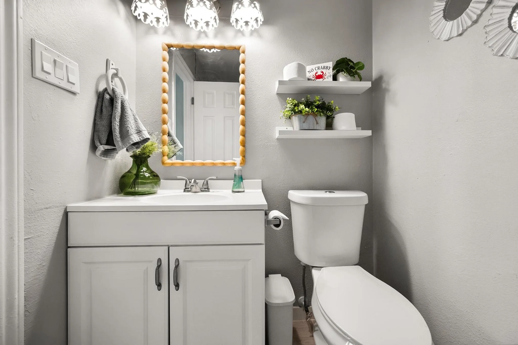 White vanity with a single sink, chrome faucet, and bead-framed mirror