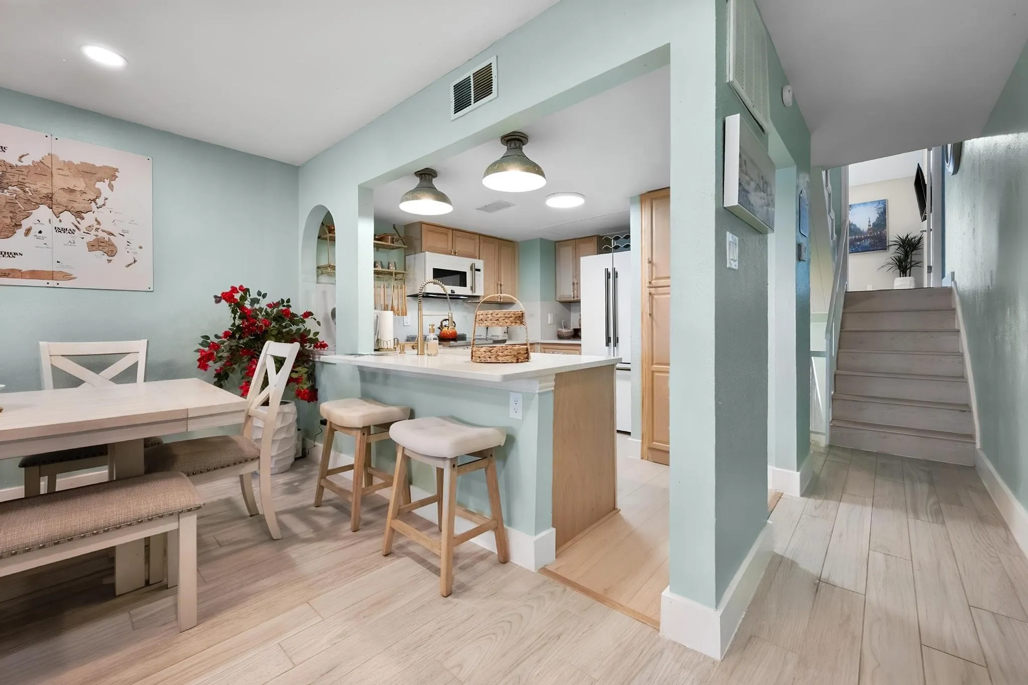 Kitchen featuring wood cabinetry, white appliances, and a breakfast bar with pendant lighting