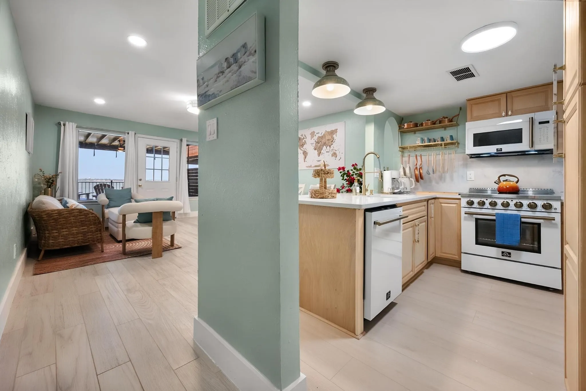 Kitchen featuring light wood cabinetry, white countertops, built-in microwave, and stainless steel range