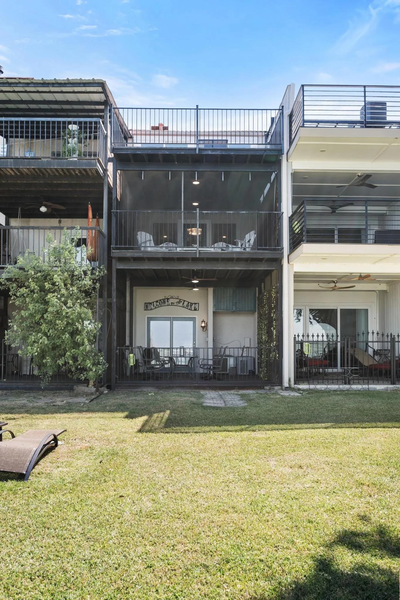 Multi-level property featuring a ground-level patio, a screened second-level balcony, and an open-air top-level balcony