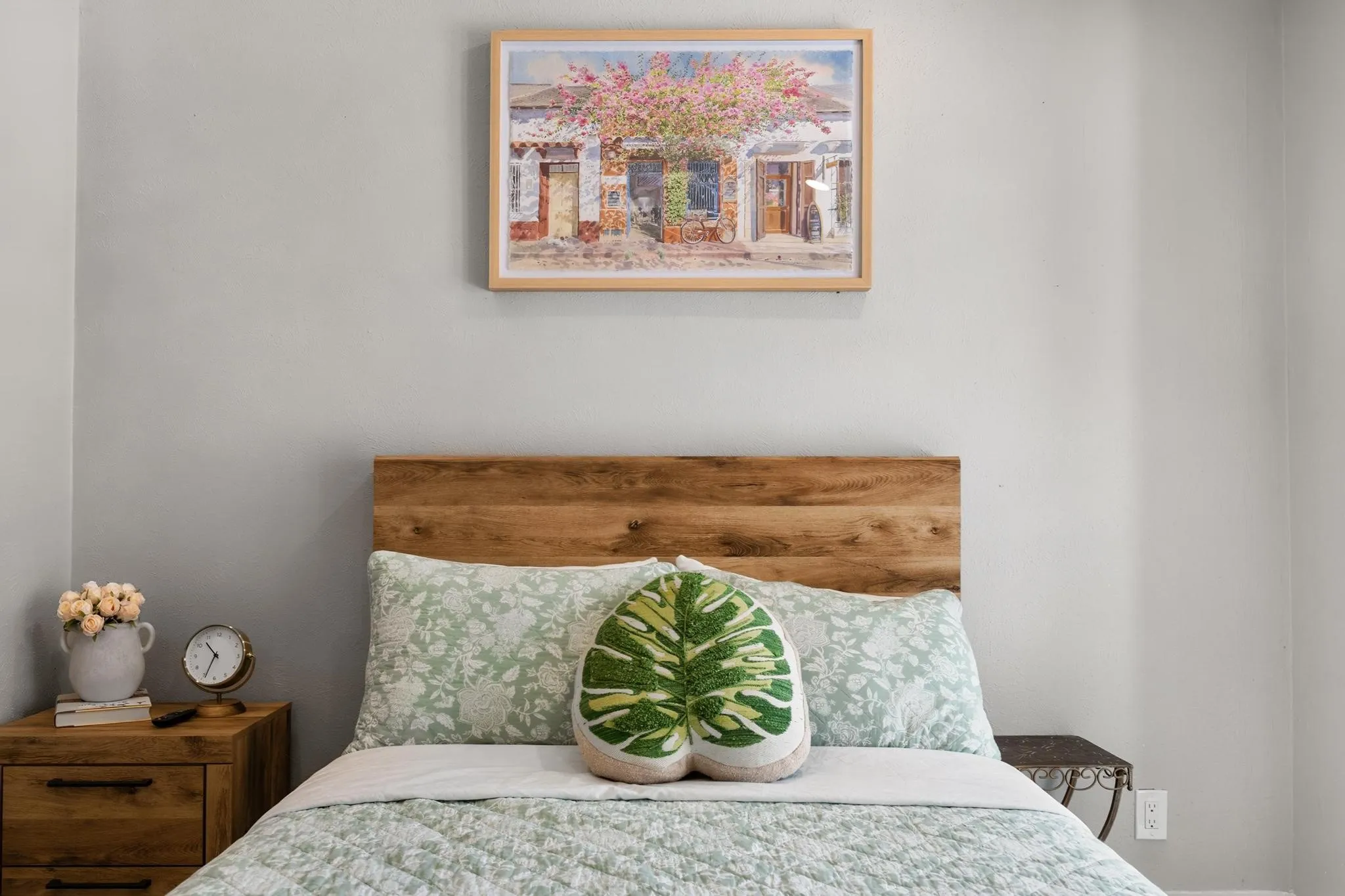 Wood-finish headboard with painted walls and a wood-finish nightstand featuring metal hardware