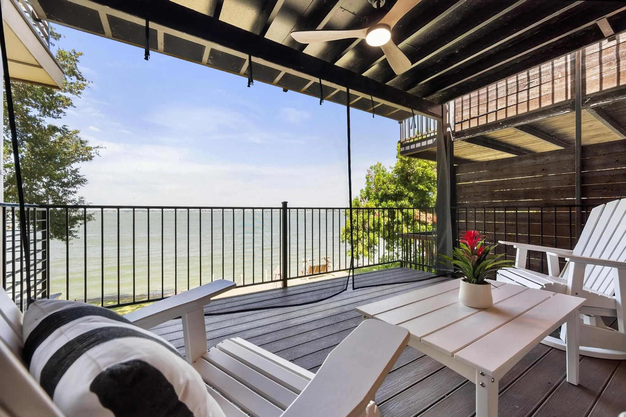 Covered balcony with composite decking, black metal railing, and an overhead ceiling fan