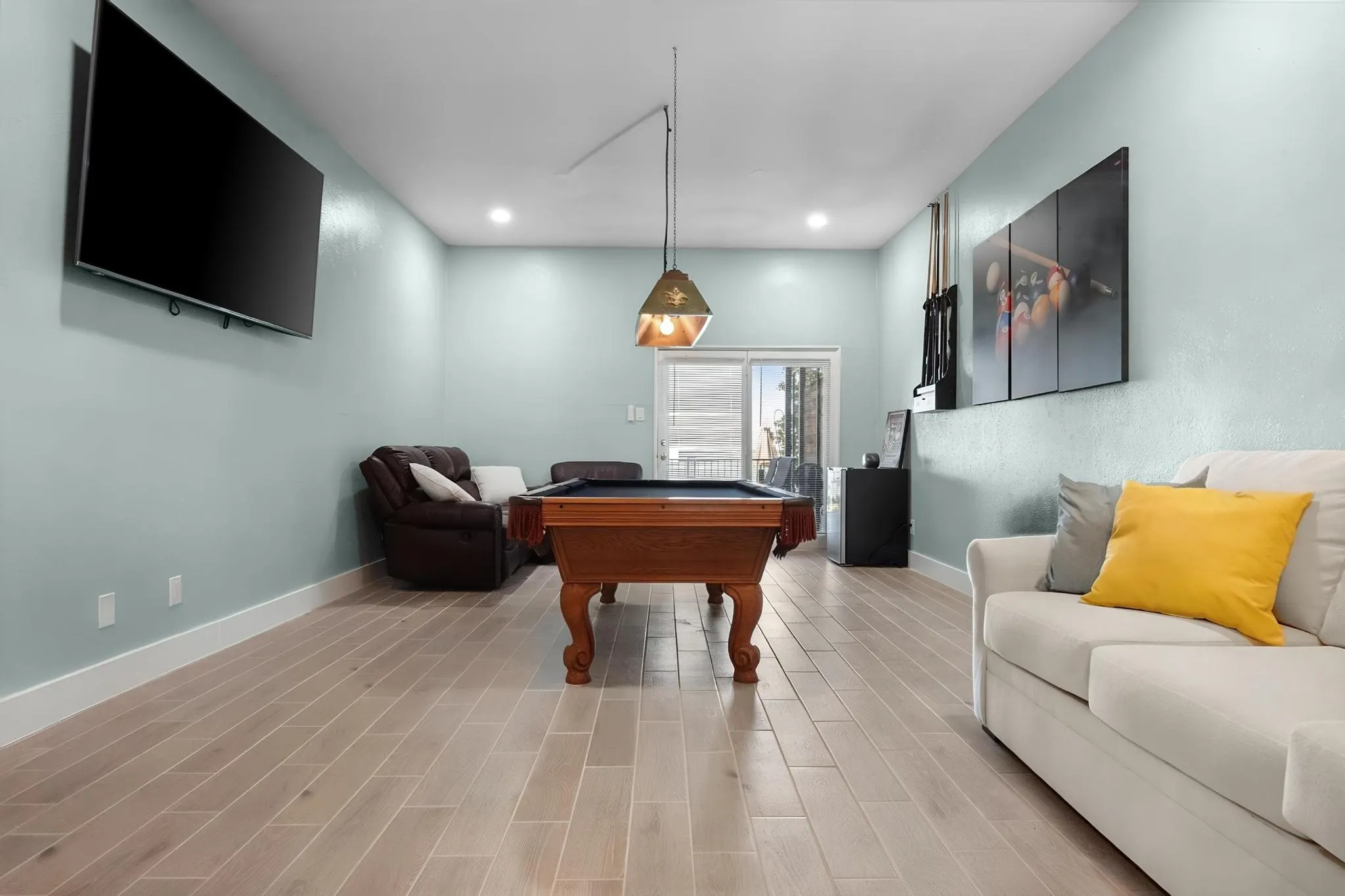 Spacious room featuring light wood-finish flooring, recessed lighting, and a sliding glass door