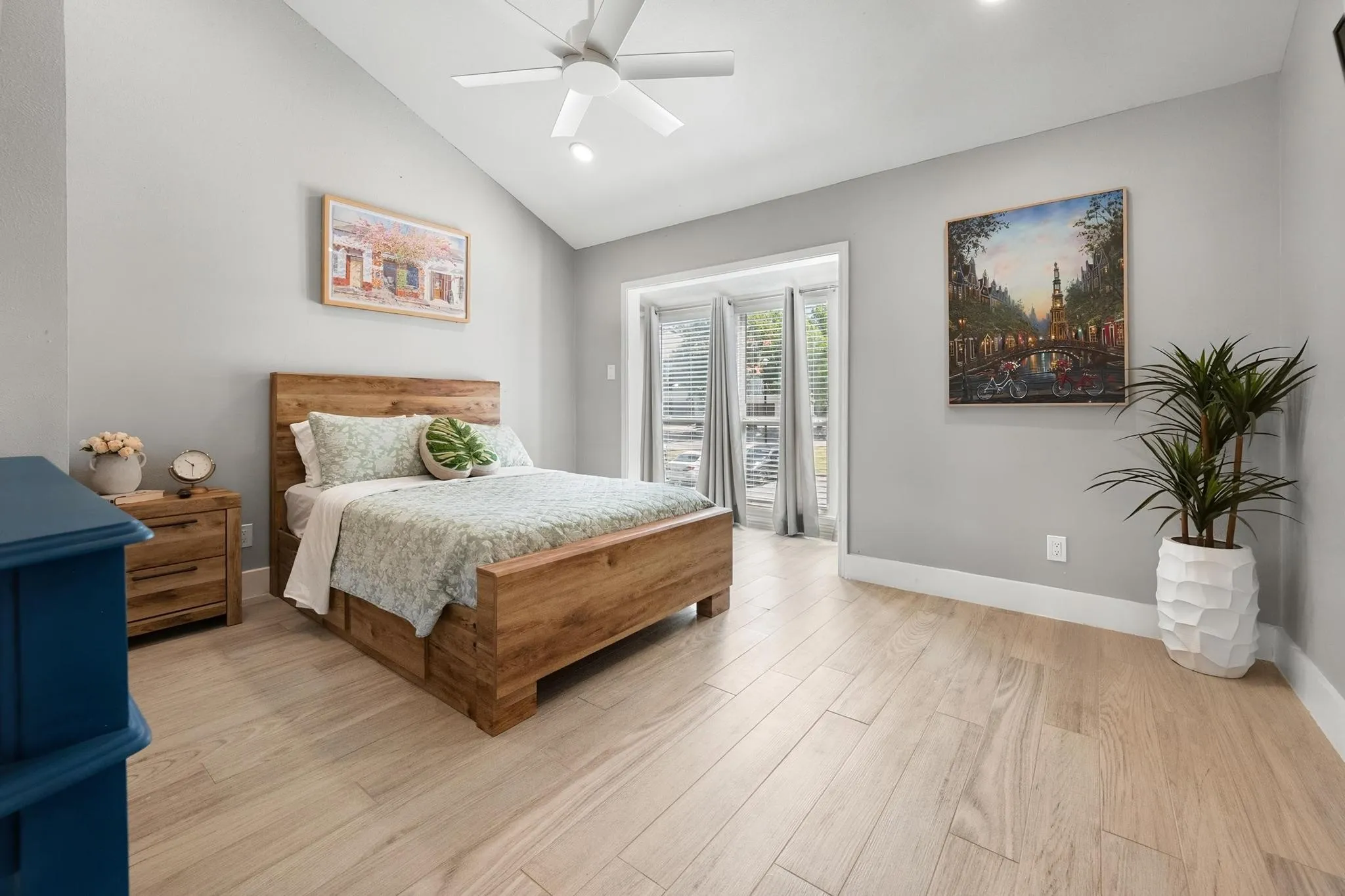 Vaulted ceiling with a ceiling fan, light wood-finish flooring, and double French doors with blinds
