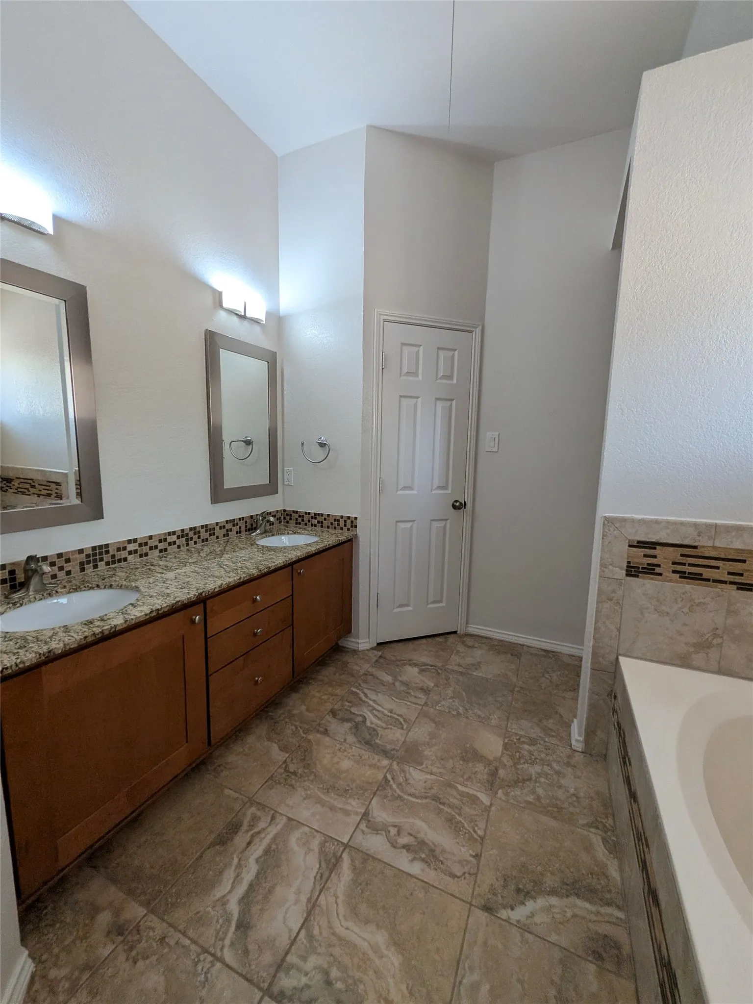 Dual vanity with granite countertops, mosaic tile backsplash, and integrated sinks
