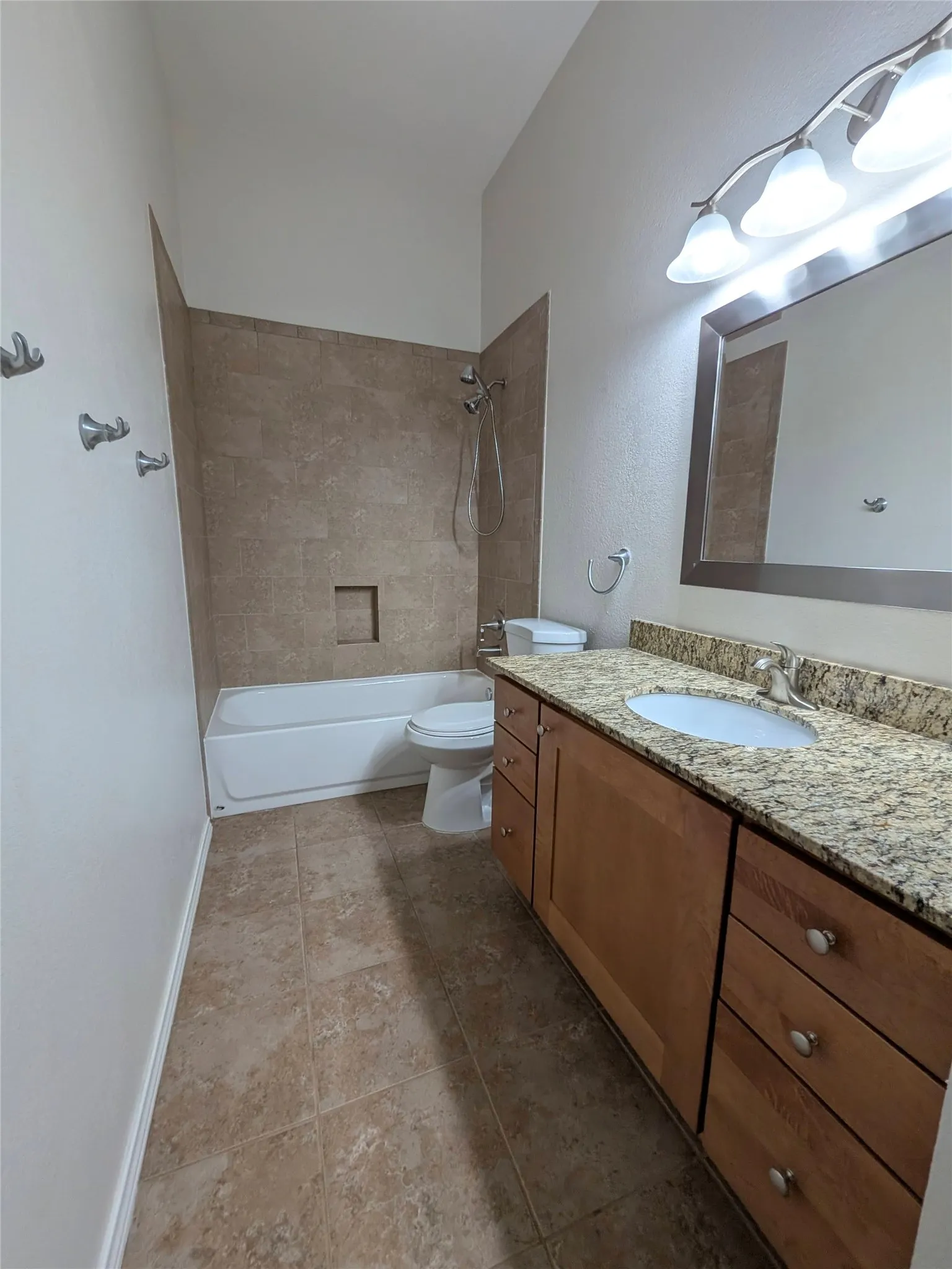 Vanity with a granite-style countertop, undermount sink, and wood-finish cabinetry