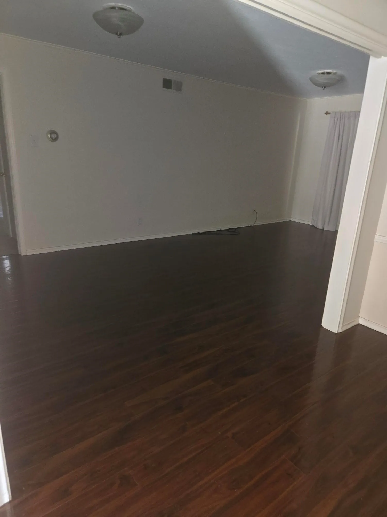 Expansive room featuring dark wood-finish flooring, white walls, and flush-mount ceiling lights