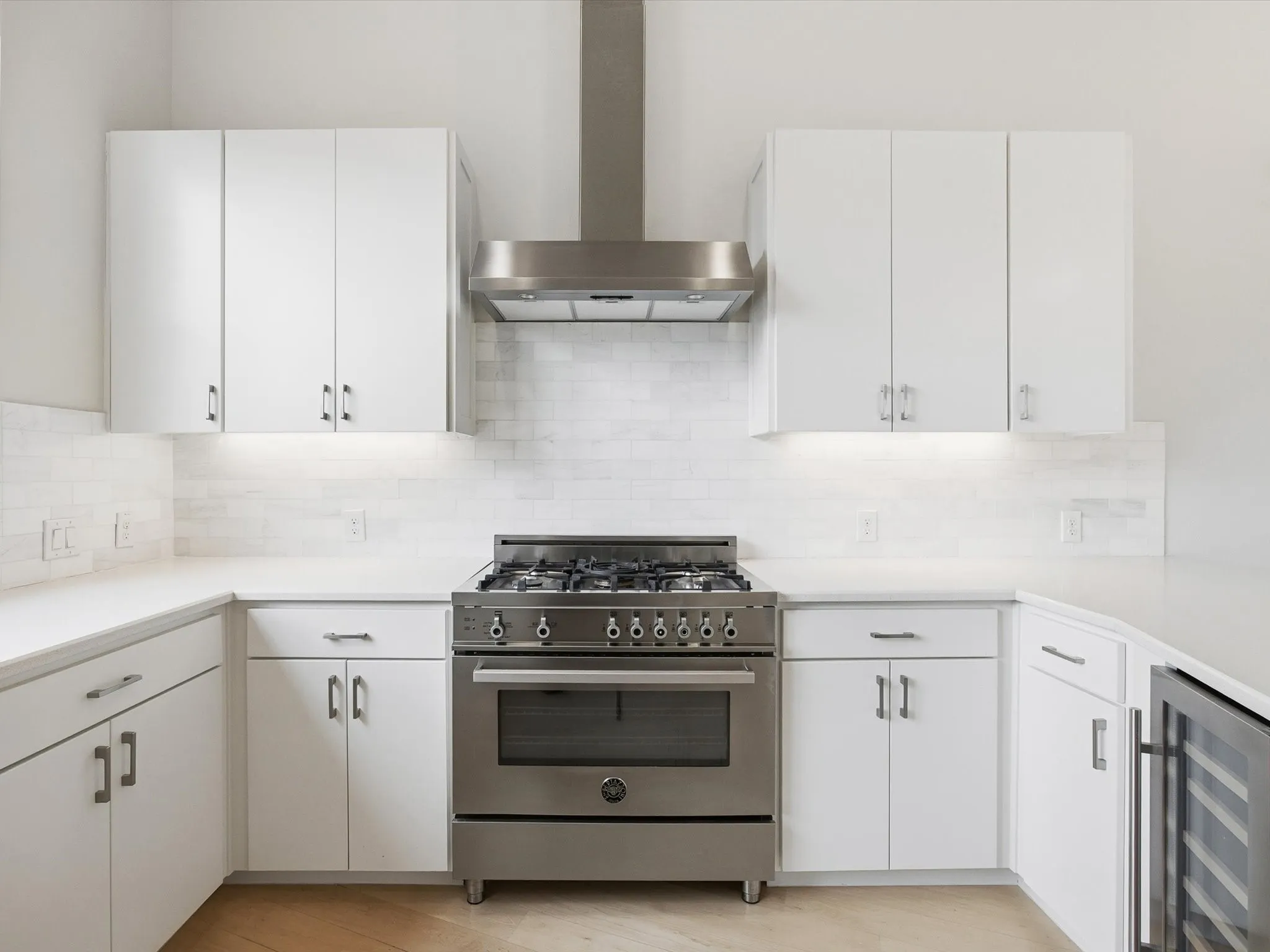Kitchen featuring wall chimney exhaust hood, stainless steel range, and white cabinets