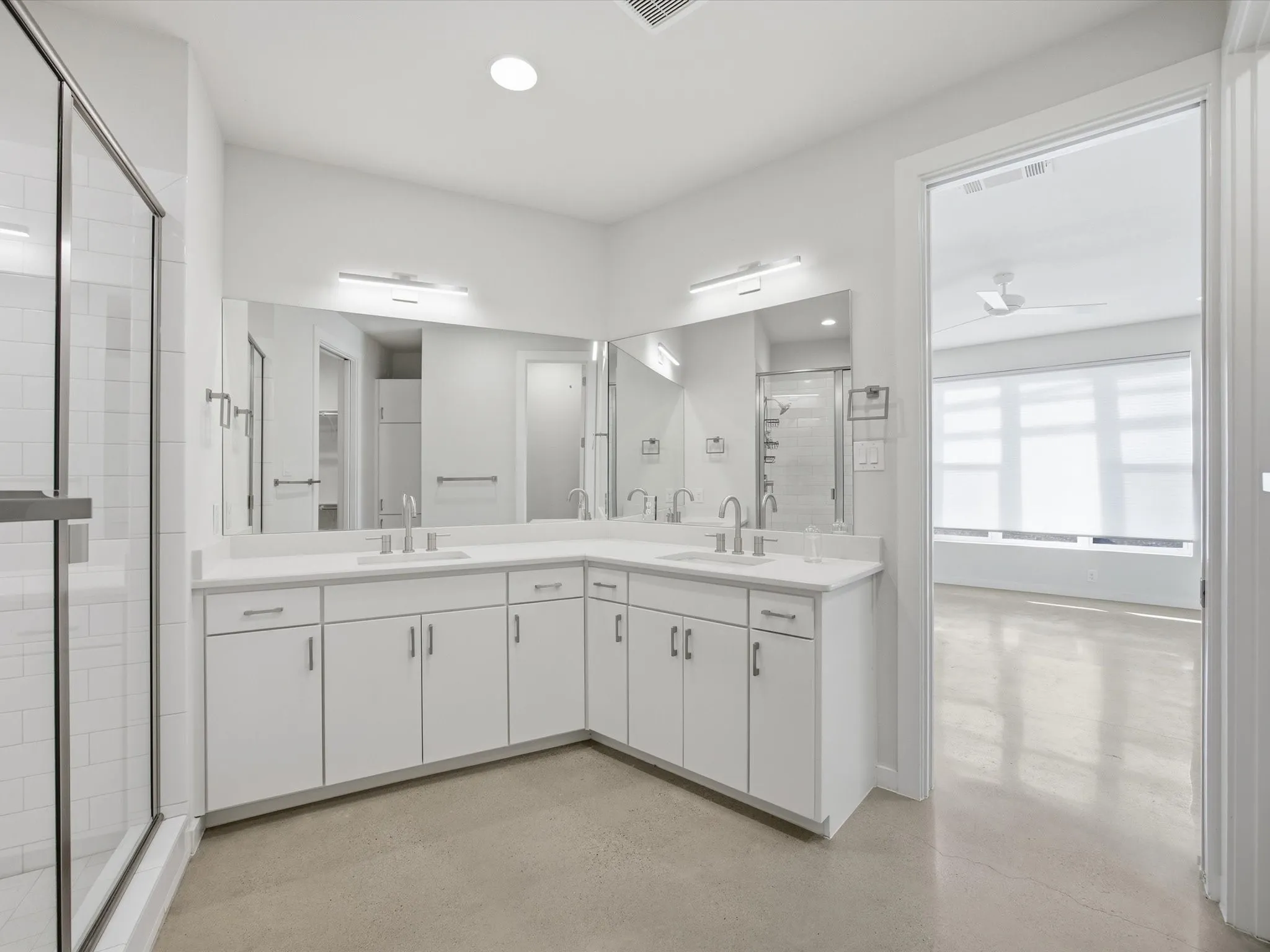 Full bath with double vanity, a stall shower, and a ceiling fan