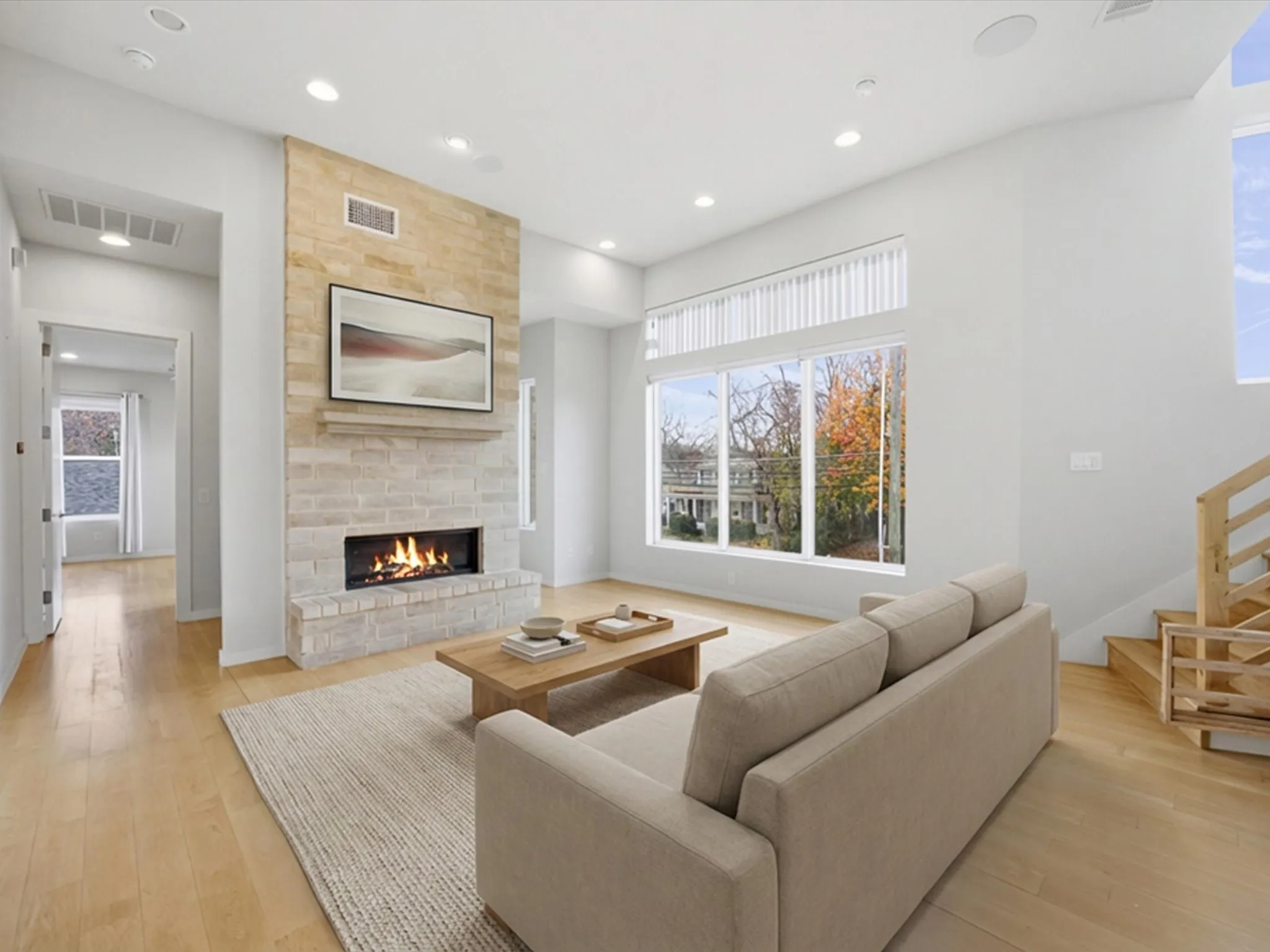 Living room featuring a large fireplace, light wood-style flooring, recessed lighting, and stairs