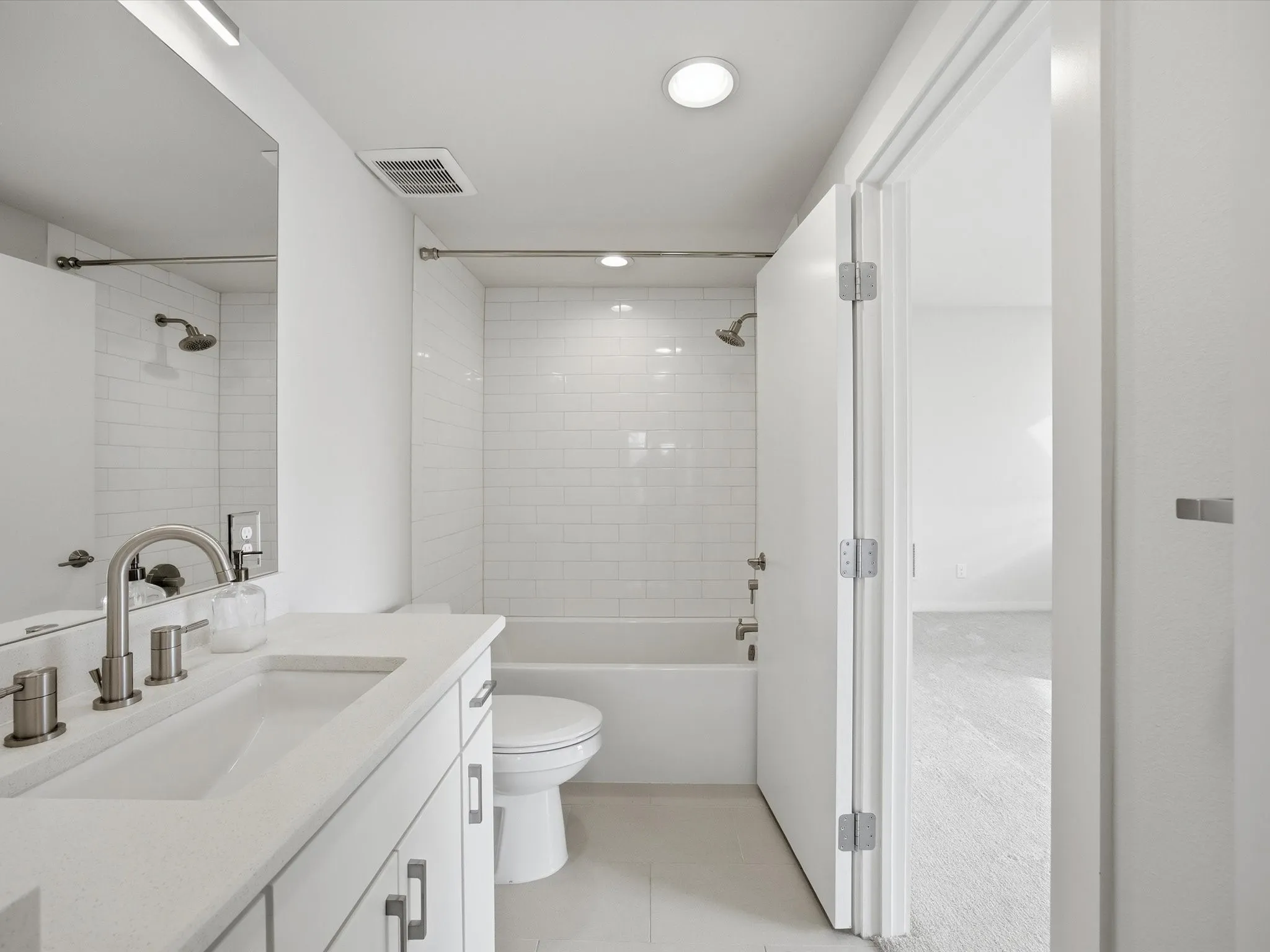 Bathroom featuring shower / washtub combination, vanity, light tile patterned floors, and recessed lighting