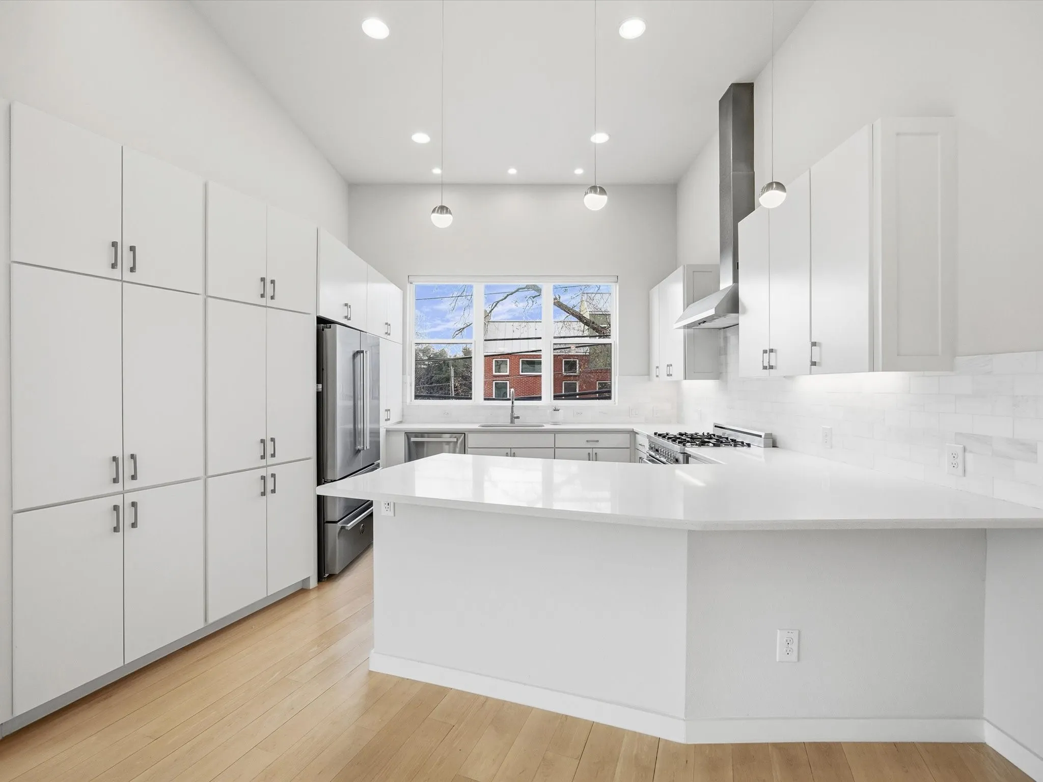 Kitchen with decorative light fixtures, a peninsula, stainless steel appliances, recessed lighting, and white cabinets