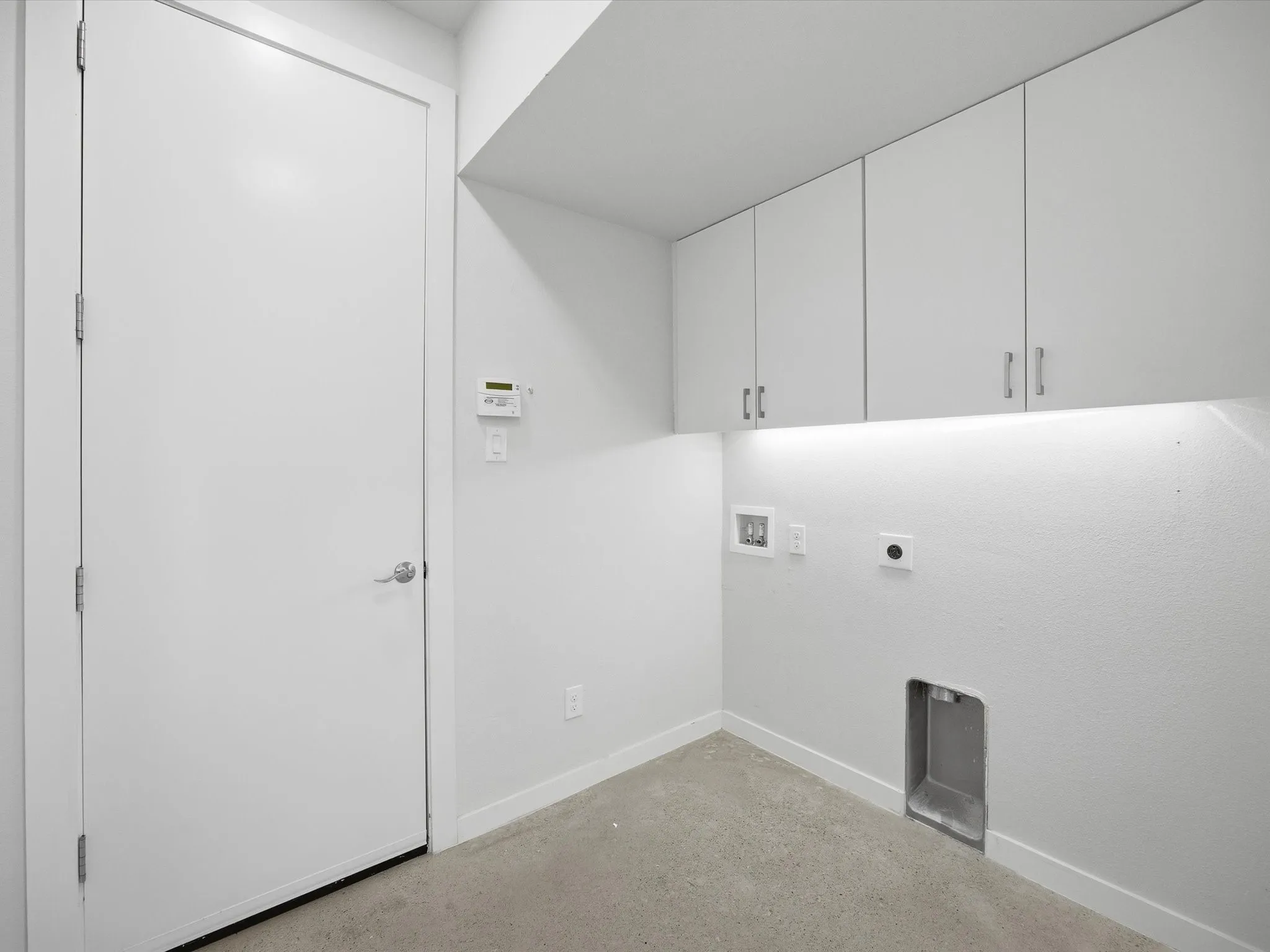 Laundry room with washer hookup, electric dryer hookup, concrete floors, and cabinet space