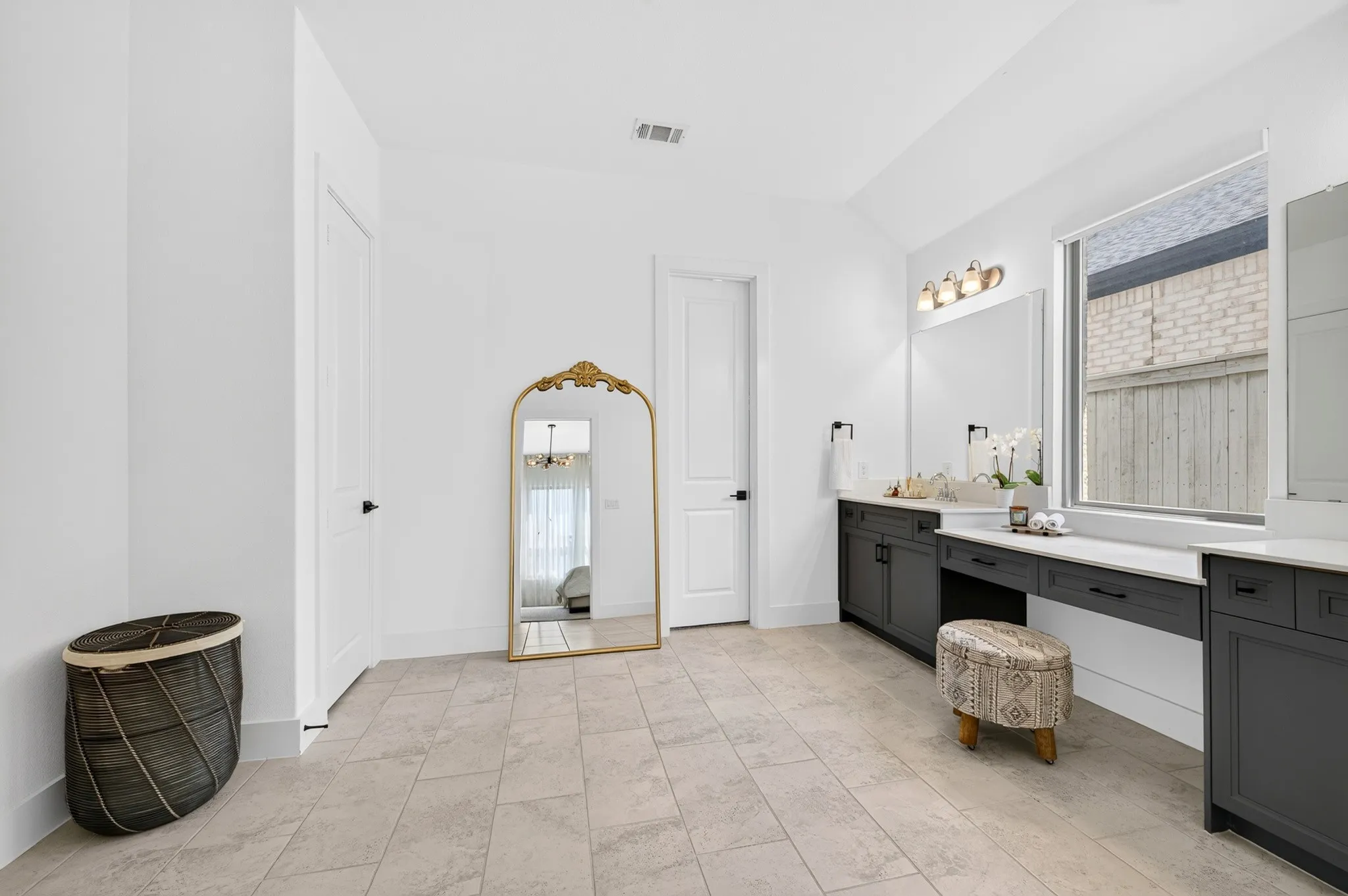 Spacious room featuring tile flooring, a large window, a double vanity with ample counter space, built-in cabinetry, and modern light fixtures