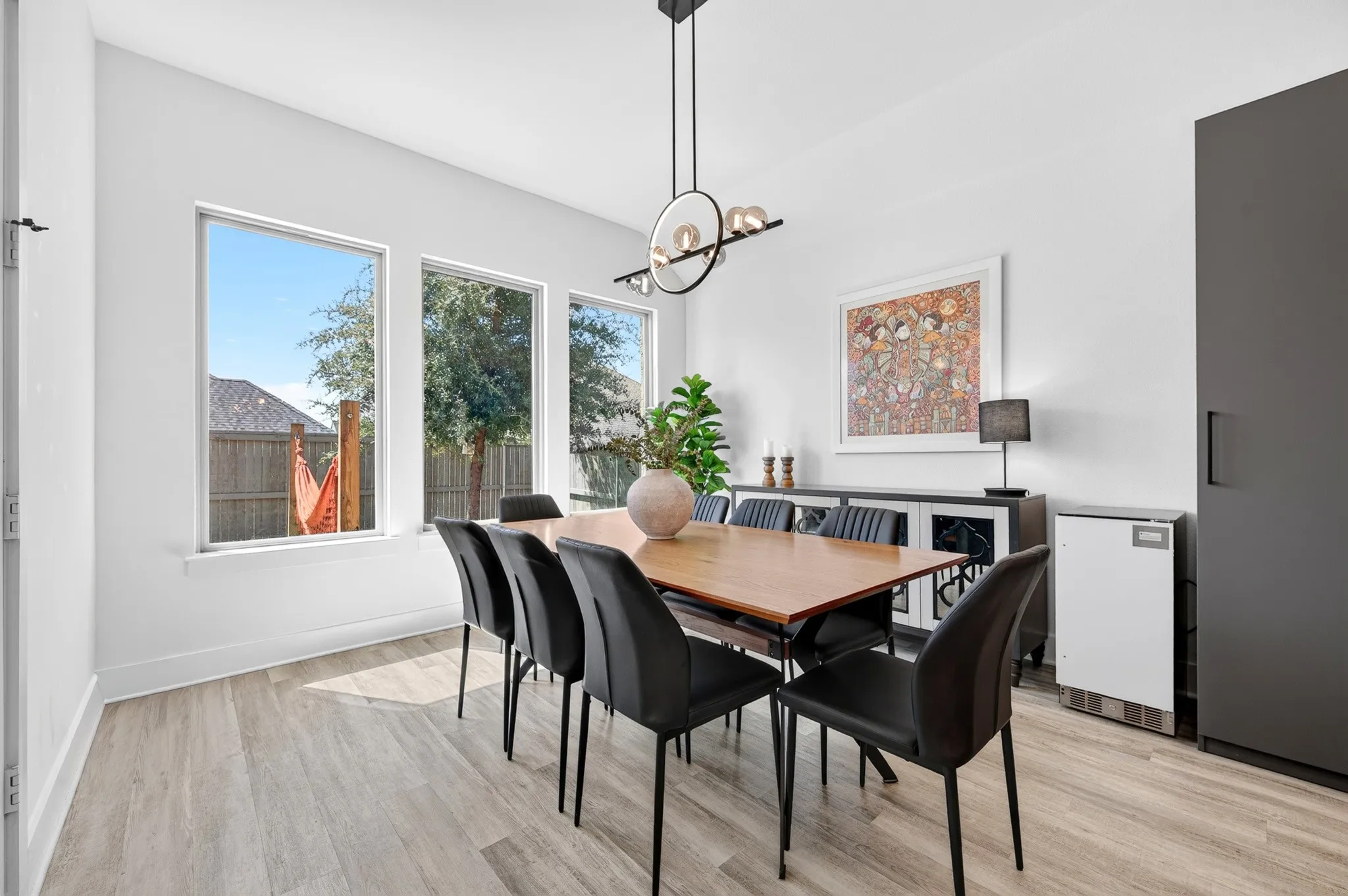 Spacious dining area featuring wood-finish flooring, multiple large windows, a contemporary chandelier, and recessed lighting