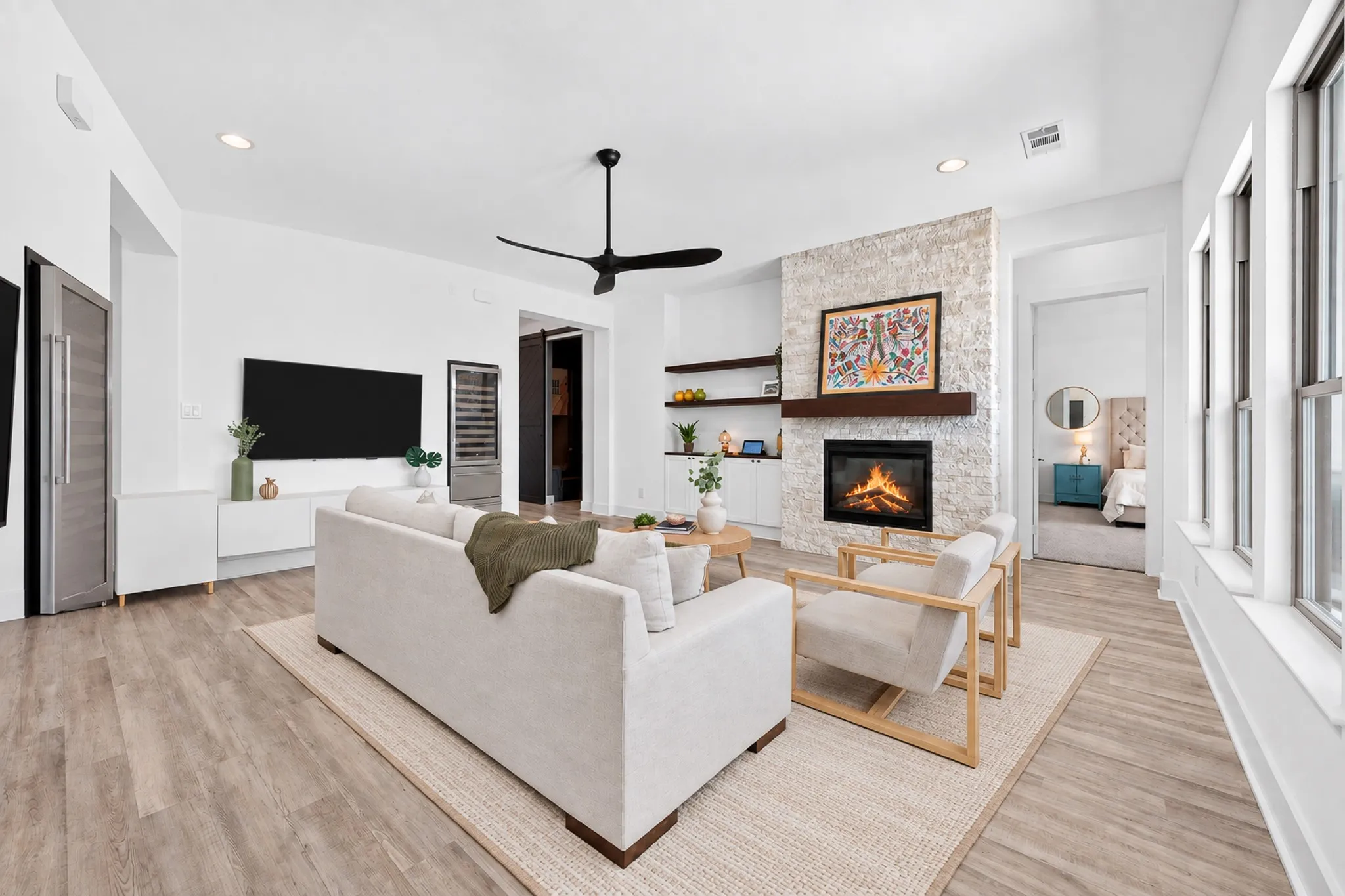 White stone-clad fireplace with a wood mantle, wood-finish flooring, recessed lighting, and a contemporary ceiling fan