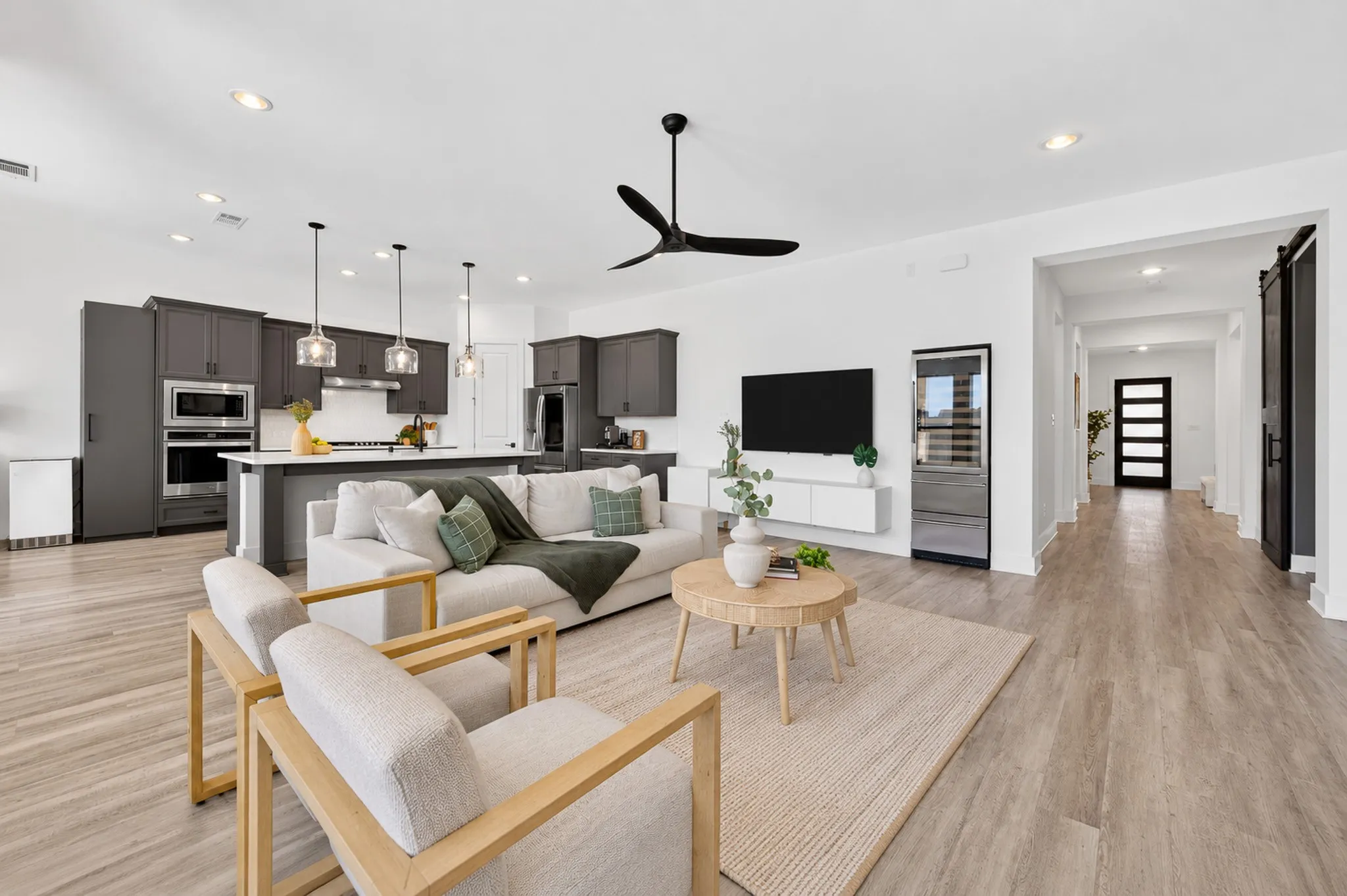 Open-concept living area with wood-finish flooring, a contemporary ceiling fan, and recessed lighting