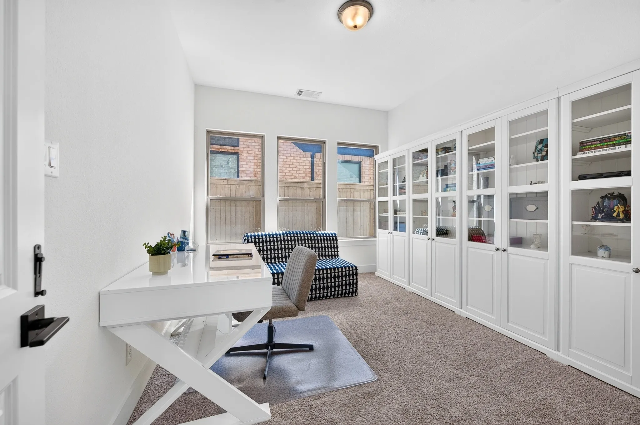 Multiple windows, recessed lighting, built-in cabinetry with glass-front doors, and neutral carpeting