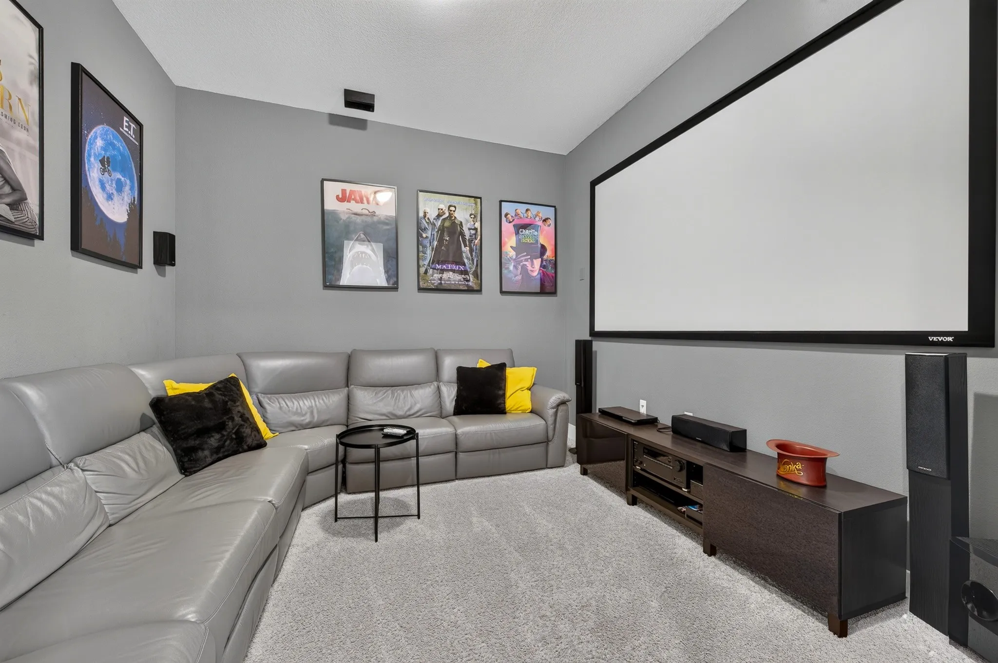 Large projection screen with dark frame, wall-mounted speakers, and a built-in media console