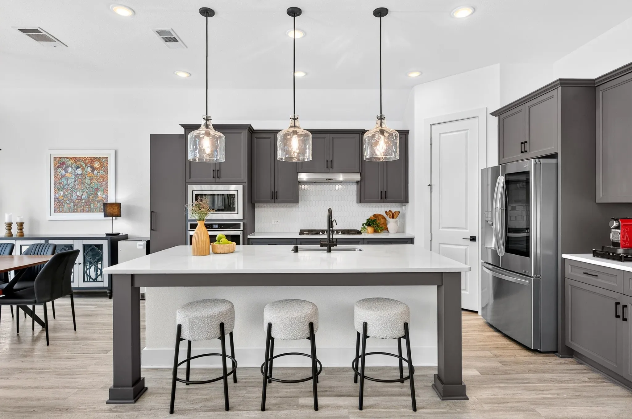 Kitchen featuring a center island with countertop seating, dark gray cabinetry, stainless steel appliances, and wood-finish flooring