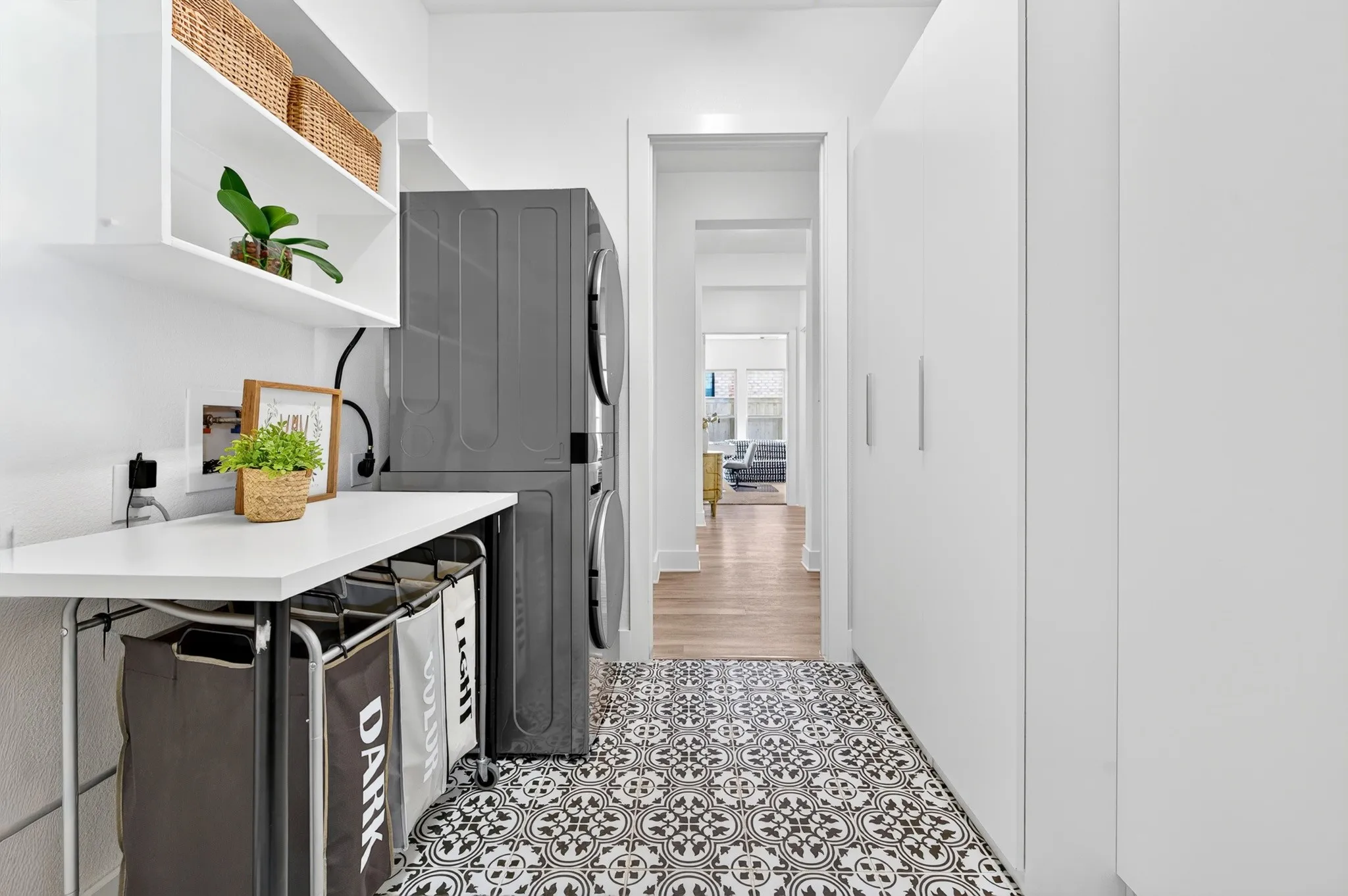 Patterned floor tiling, built-in shelving, white flat-panel cabinetry, and a dedicated laundry area with stacked appliances