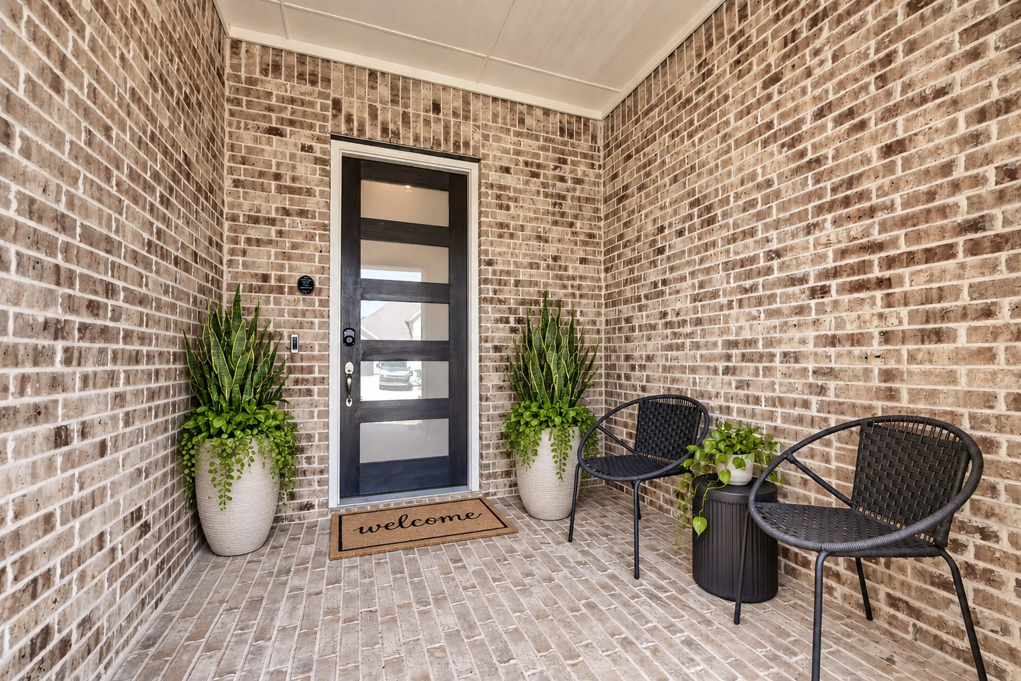 Brick exterior with a covered porch and a contemporary front door featuring frosted glass panels