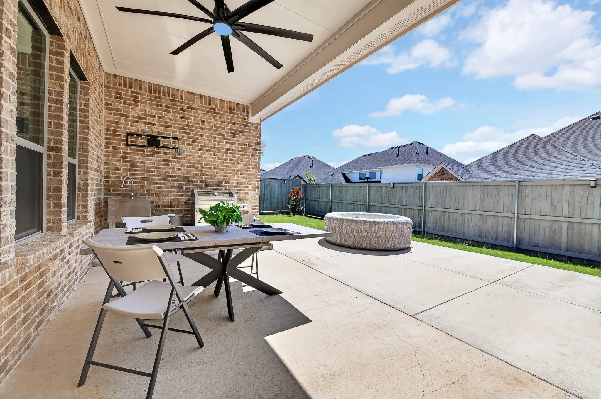 Covered patio with a ceiling fan, brick exterior, and a built-in outdoor sink